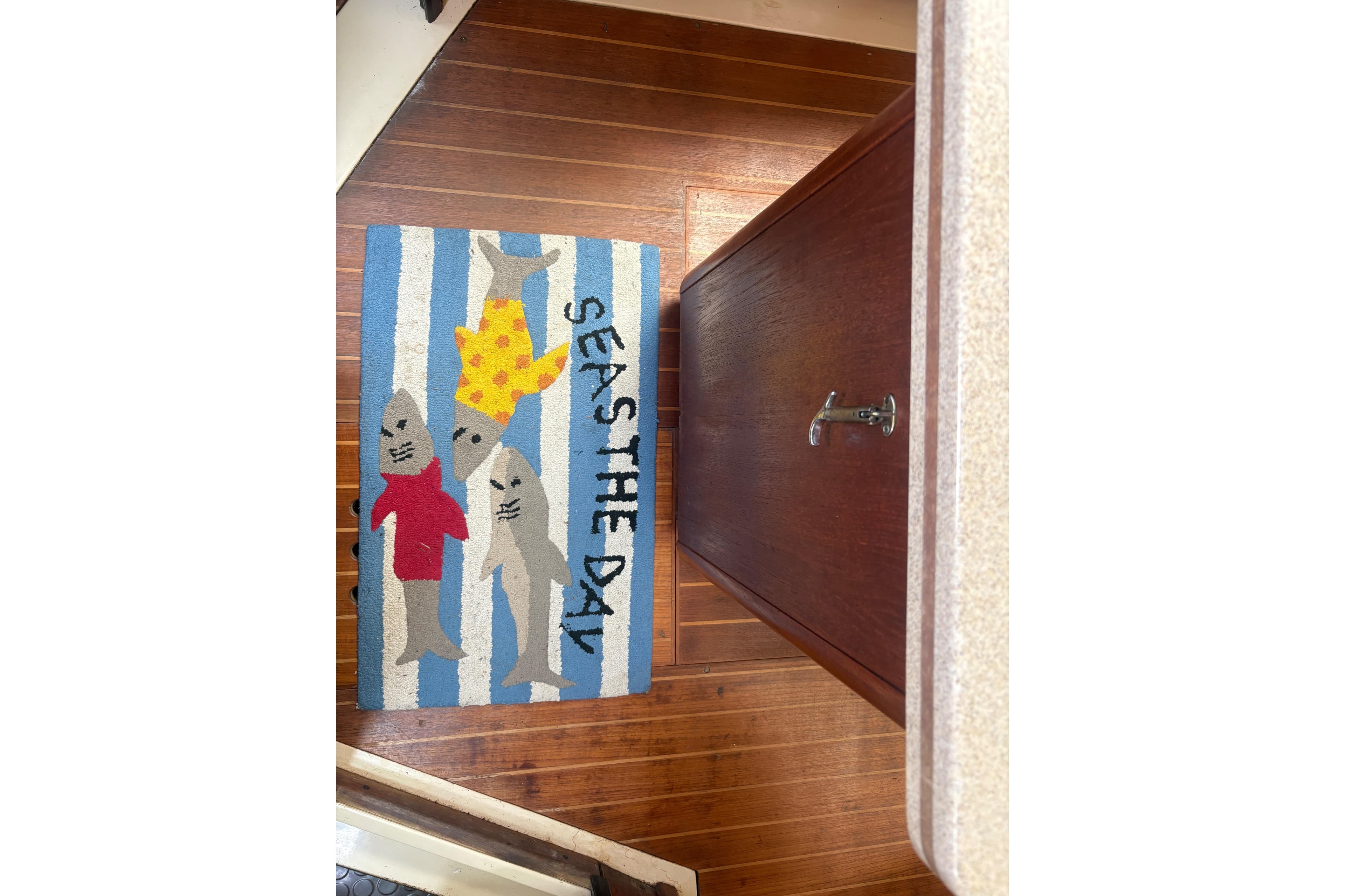 Colorful rug with sharks and "Seas the Day" text on a boat floor.