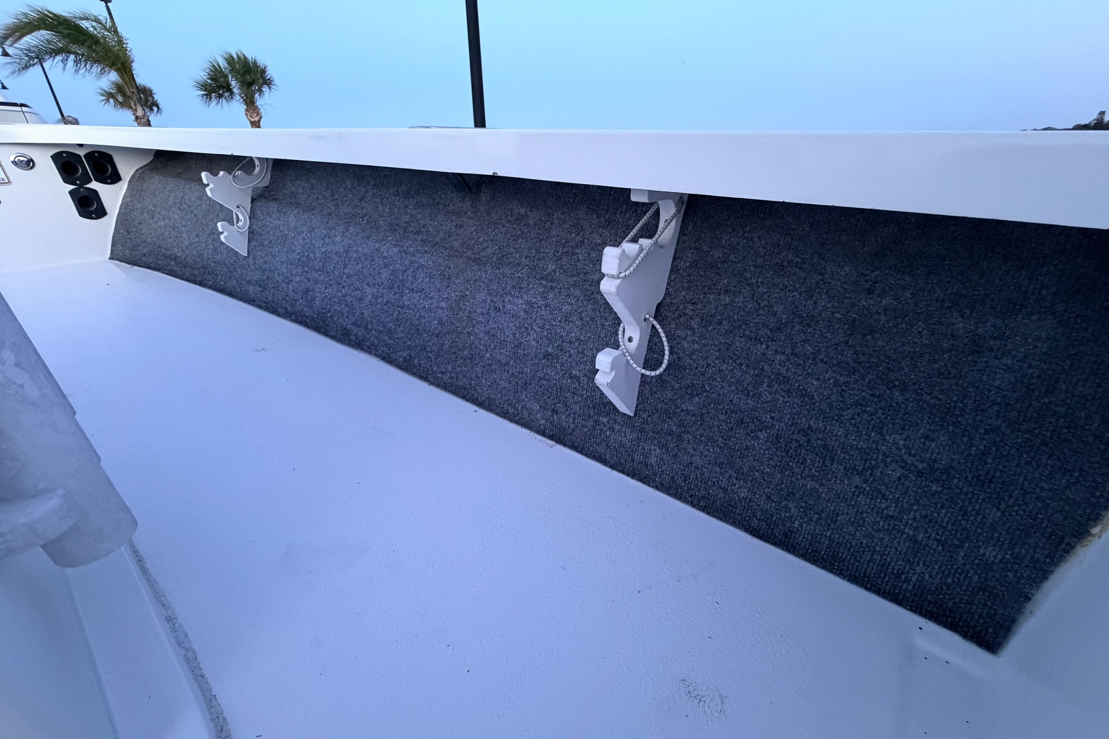 Interior view of a 2019 Mitzi Skiffs 17 boat with rod holders and carpeted side panel.