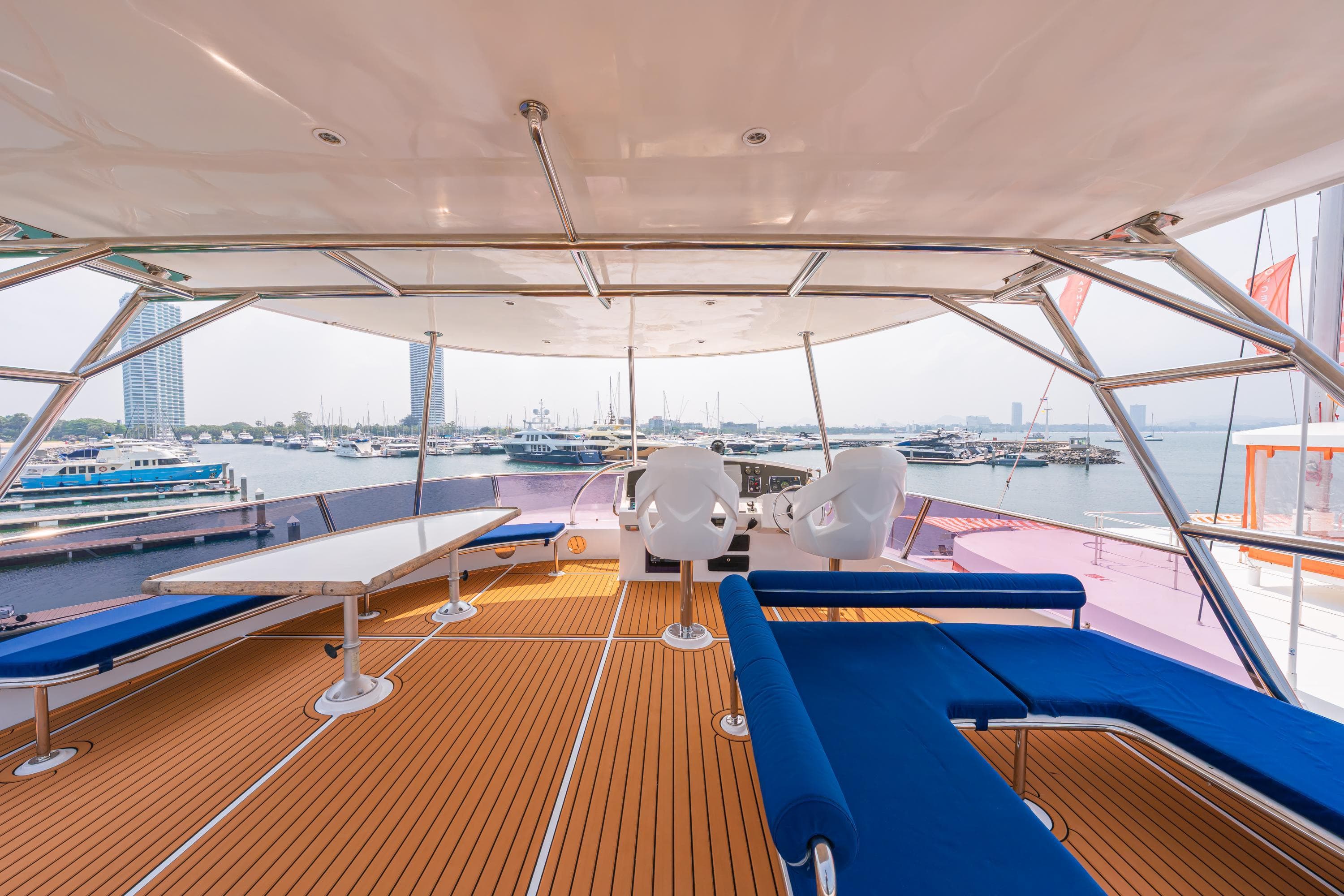 Luxurious 2023 Custom Courage 82 yacht deck with blue seating and scenic marina view.