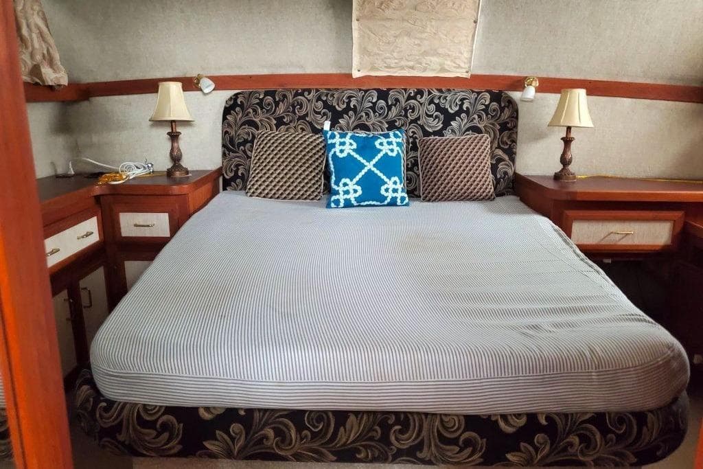 1986 Carver 3607 Aft Cabin Motor Yacht bedroom with elegant bedding and decorative pillows.