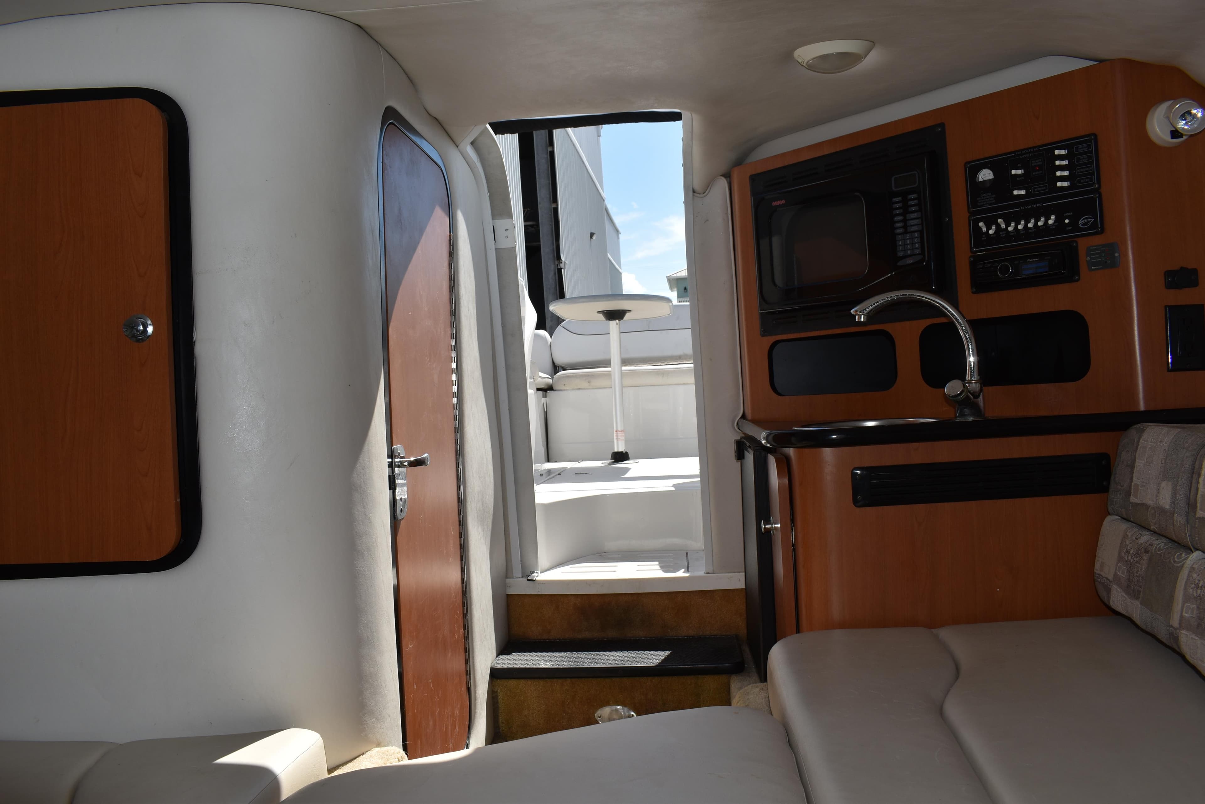 Interior of 2005 Crownline 275 CCR boat, featuring cozy seating and compact kitchenette.