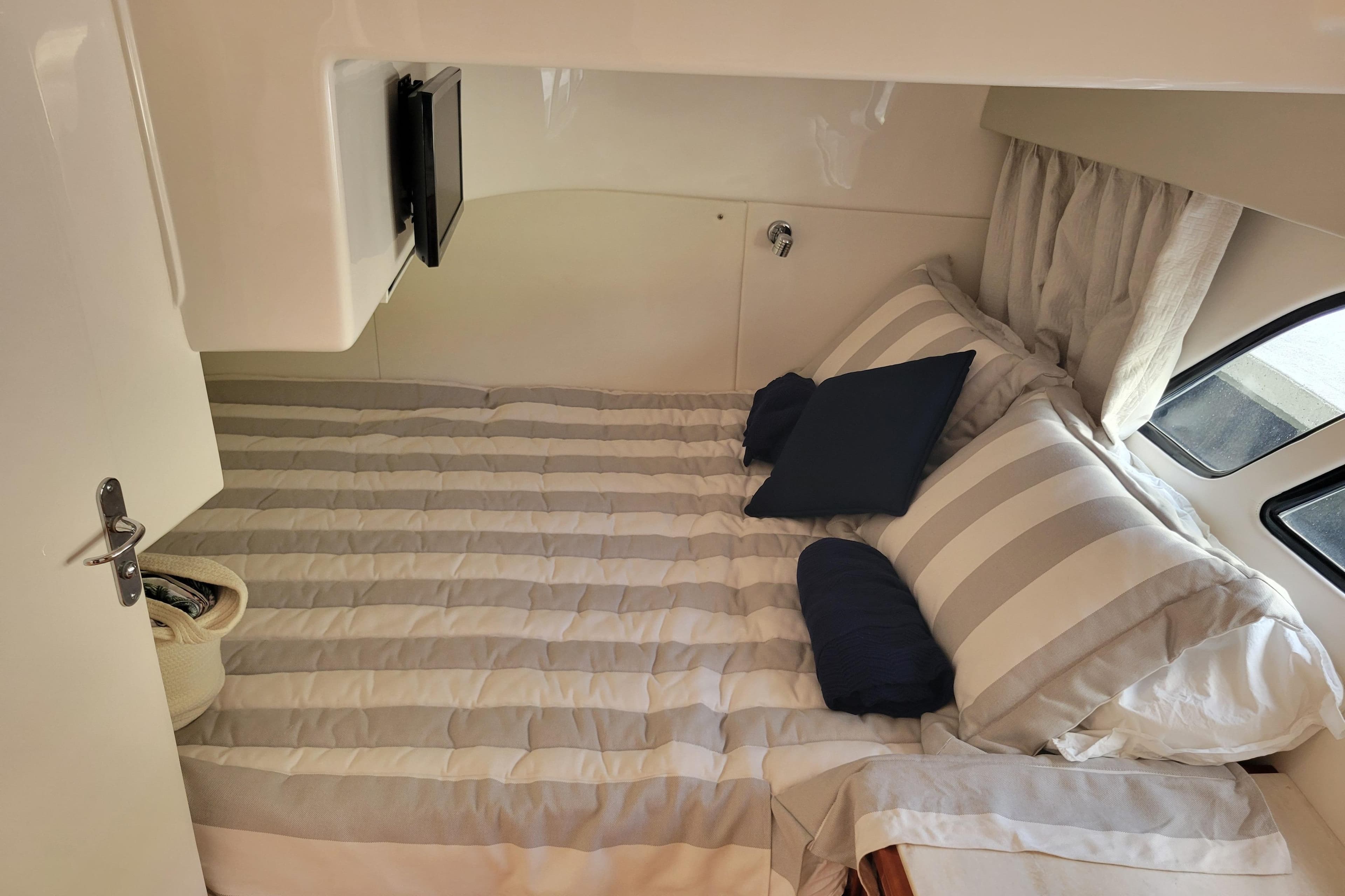 Cozy cabin interior of 2016 Intrepid 475 Sport Yacht with striped bedding and pillows.