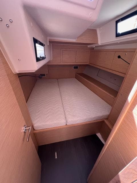 2024 Dufour 470 yacht cabin with double bed and wooden interior.