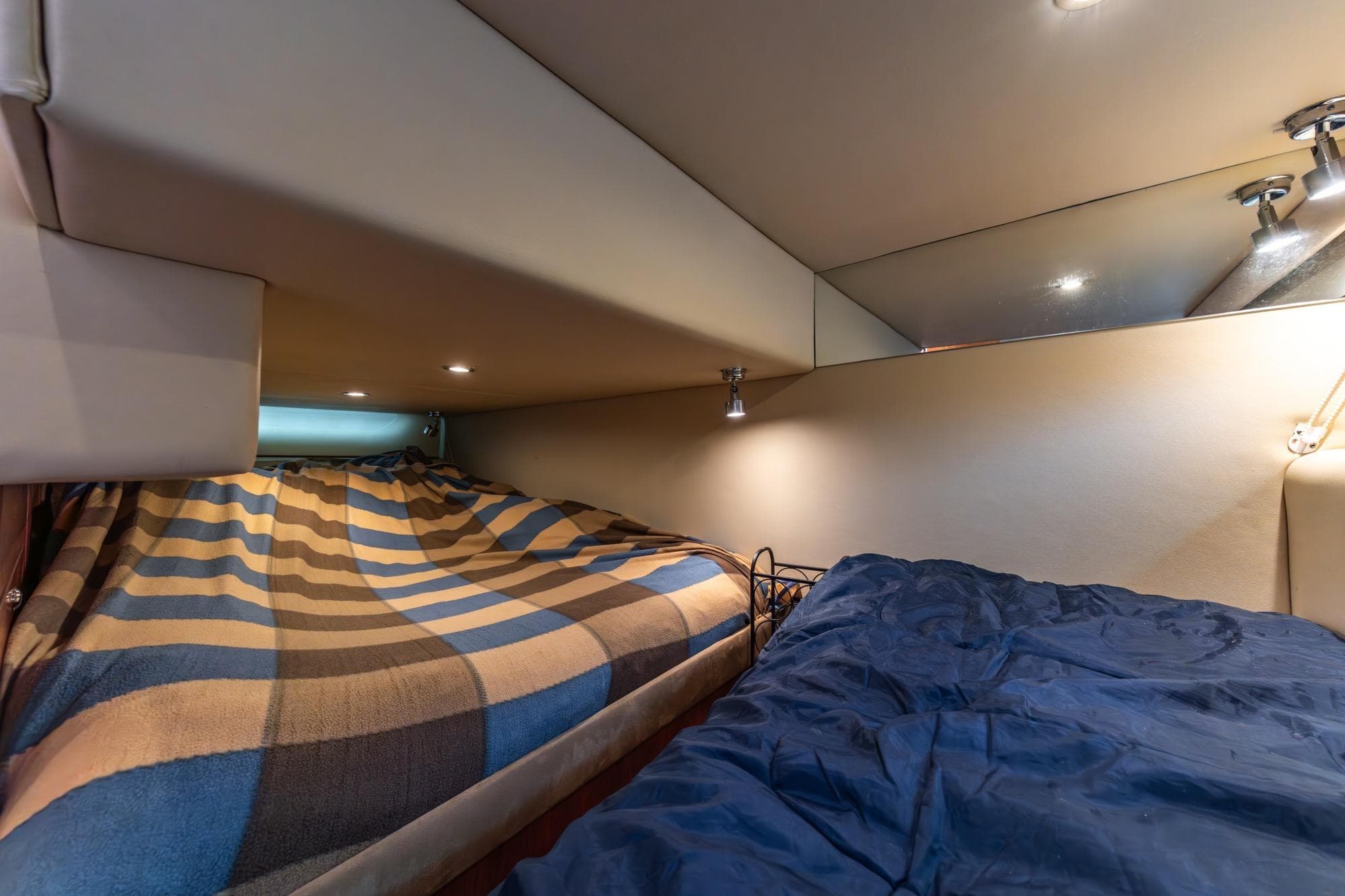 Interior cabin of 2010 Riviera 3600 Sport Yacht with cozy bedding and ambient lighting.