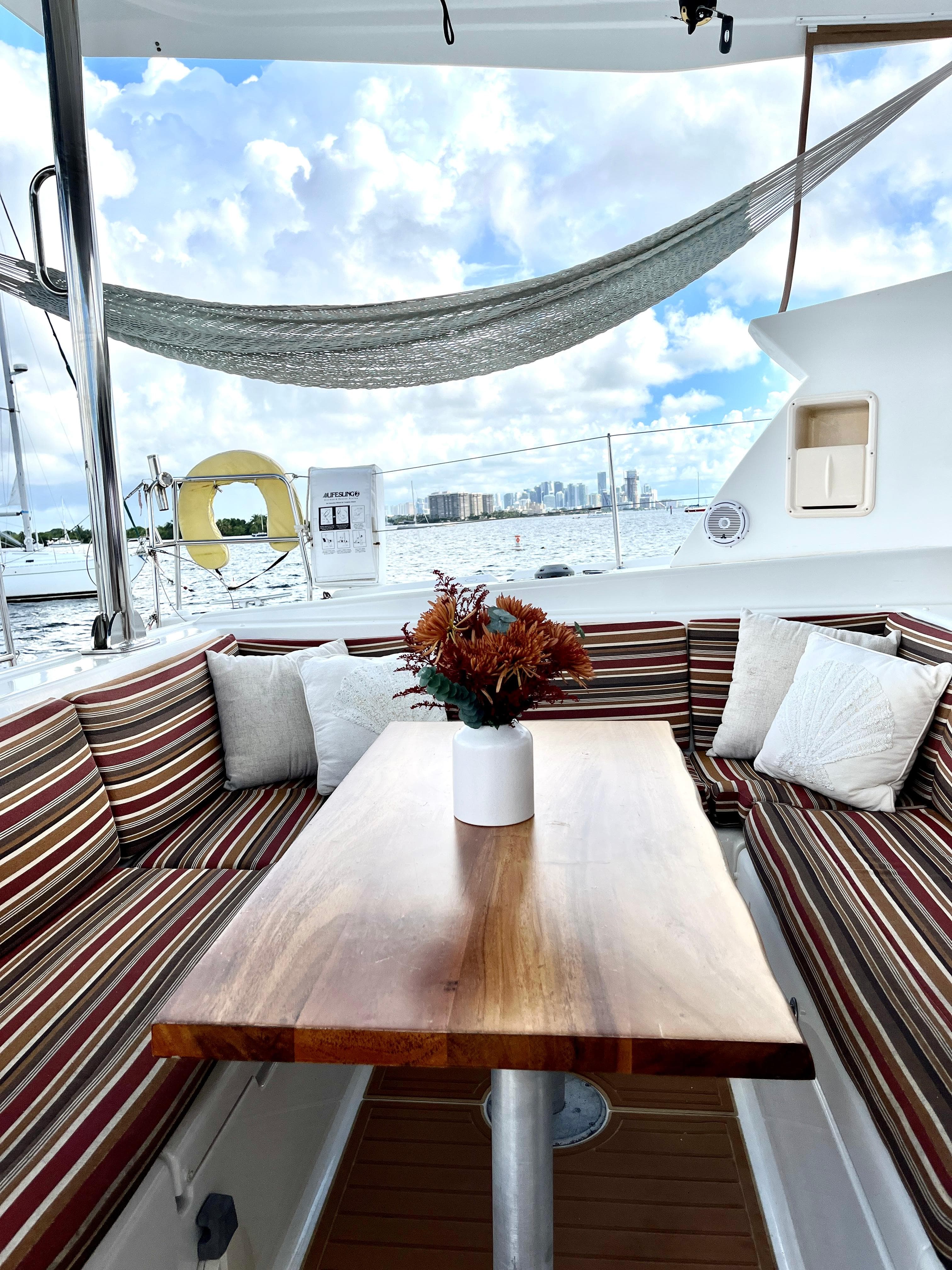 Luxurious Lagoon 420 yacht interior with striped seating, wooden table, and scenic ocean view.