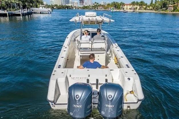 2010 Edgewater 318CC boat cruising on a scenic waterway with three passengers.