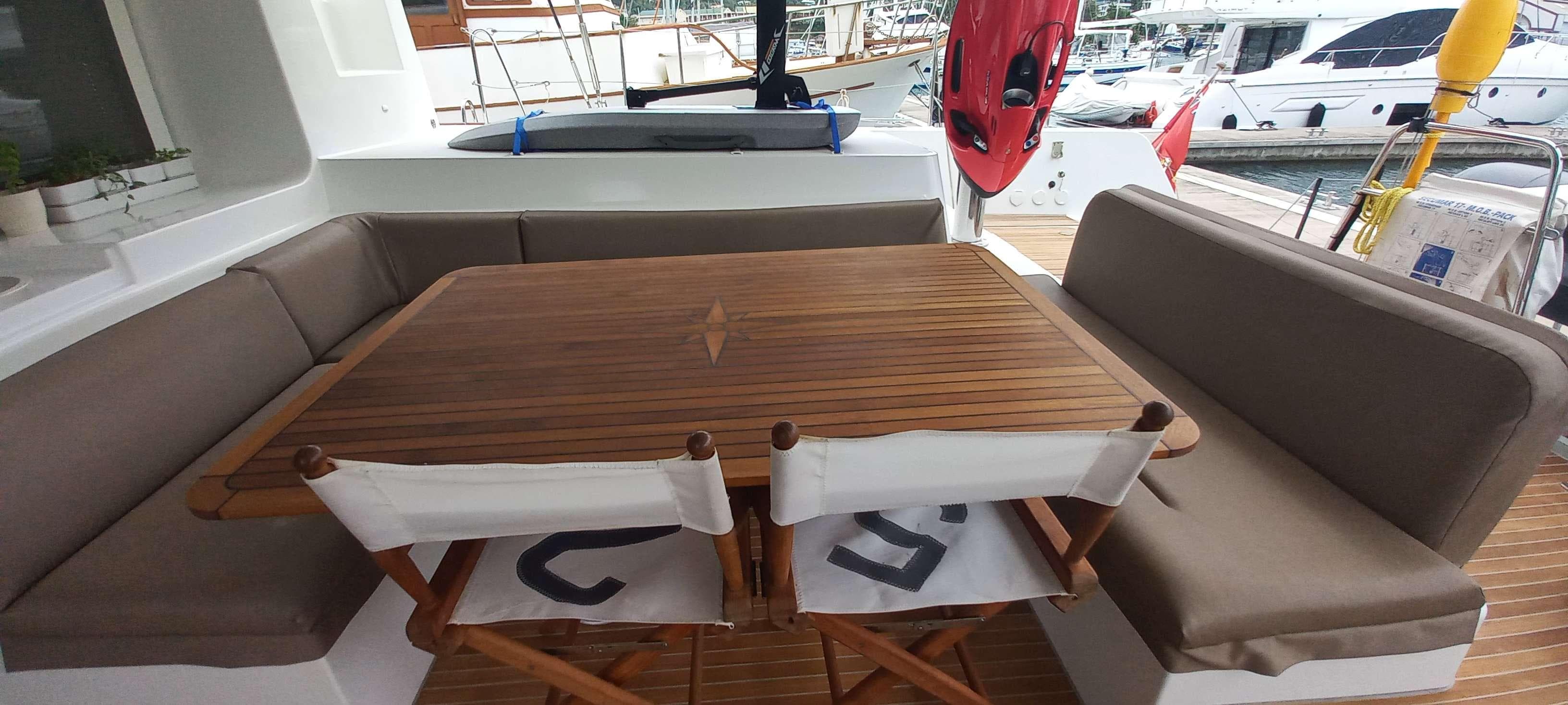 Lagoon 52 F 2014 yacht deck with wooden table, cushioned seating, and marina view.