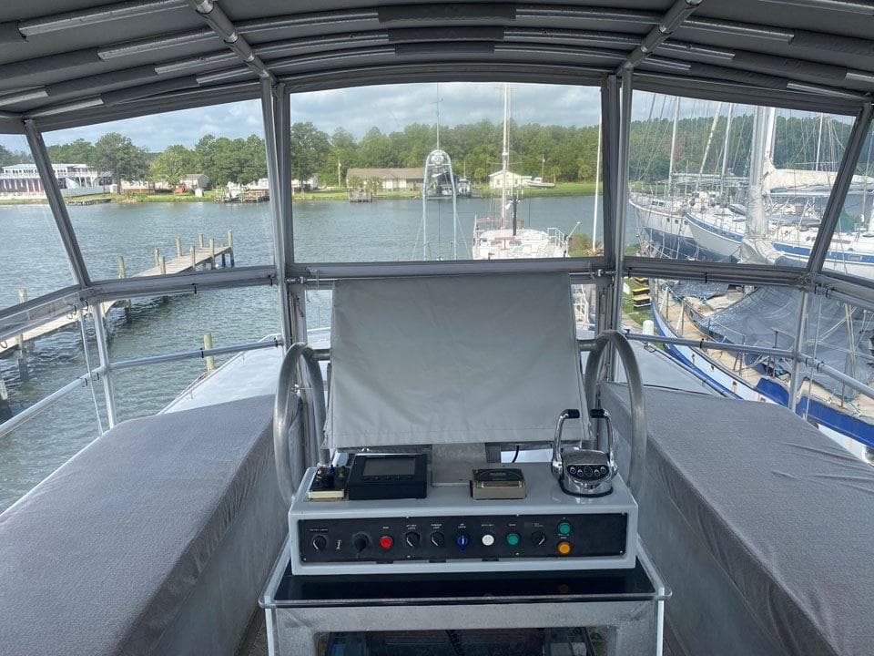 Helm of Custom FPB 83 yacht, 2005 model, overlooking marina with sailboats and docks.
