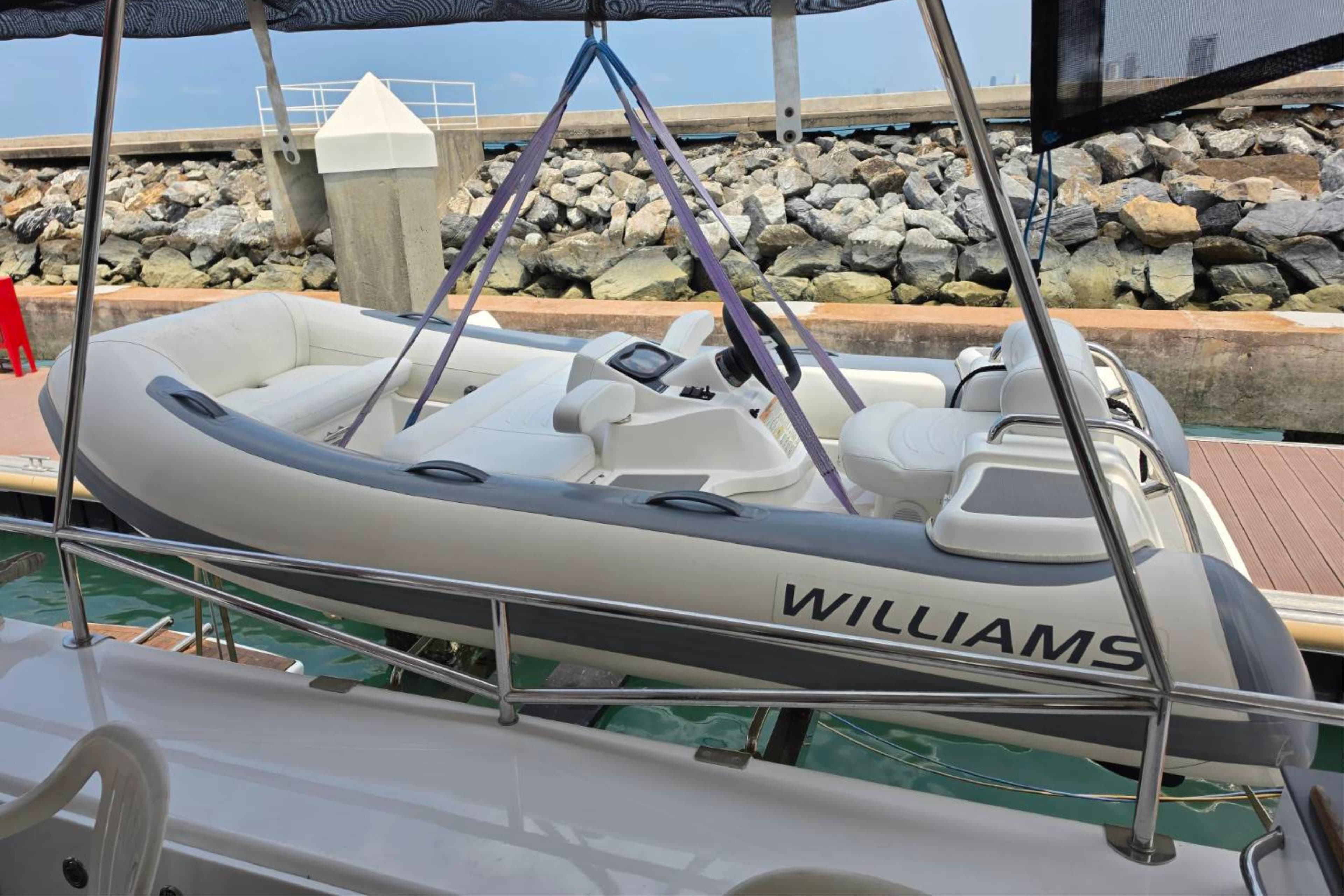 Inflatable boat on Sun Yachts Custom 56 Power Cat, 2007, docked by rocky shore.