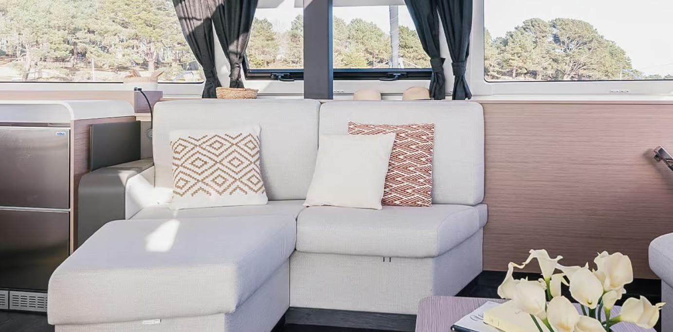 Luxurious interior of 2025 Fountaine Pajot Catamaran Aura 51 with modern sofa and scenic window view.