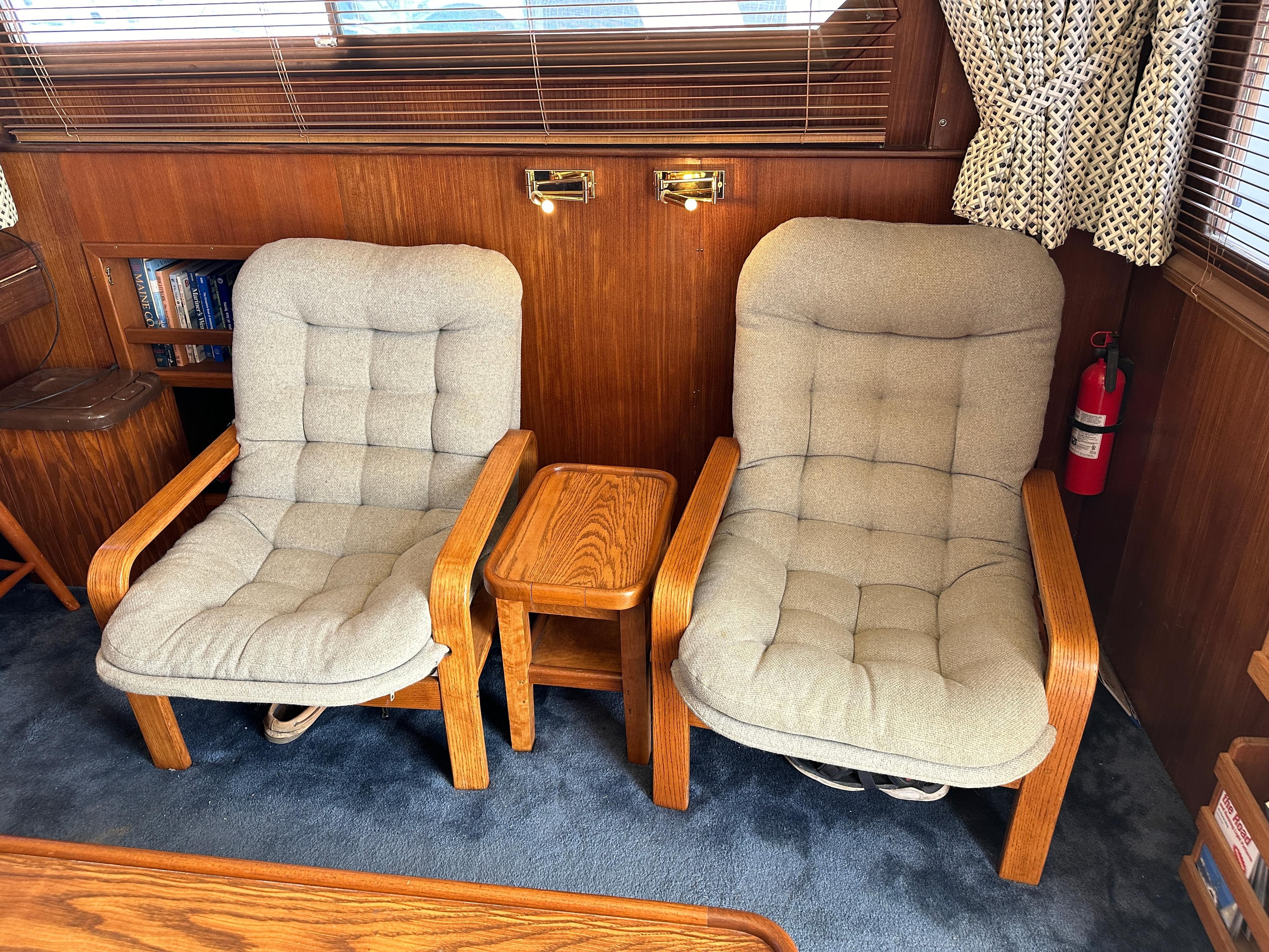 Two cushioned chairs and a small table in a 1985 Hatteras 36 Convertible yacht interior.