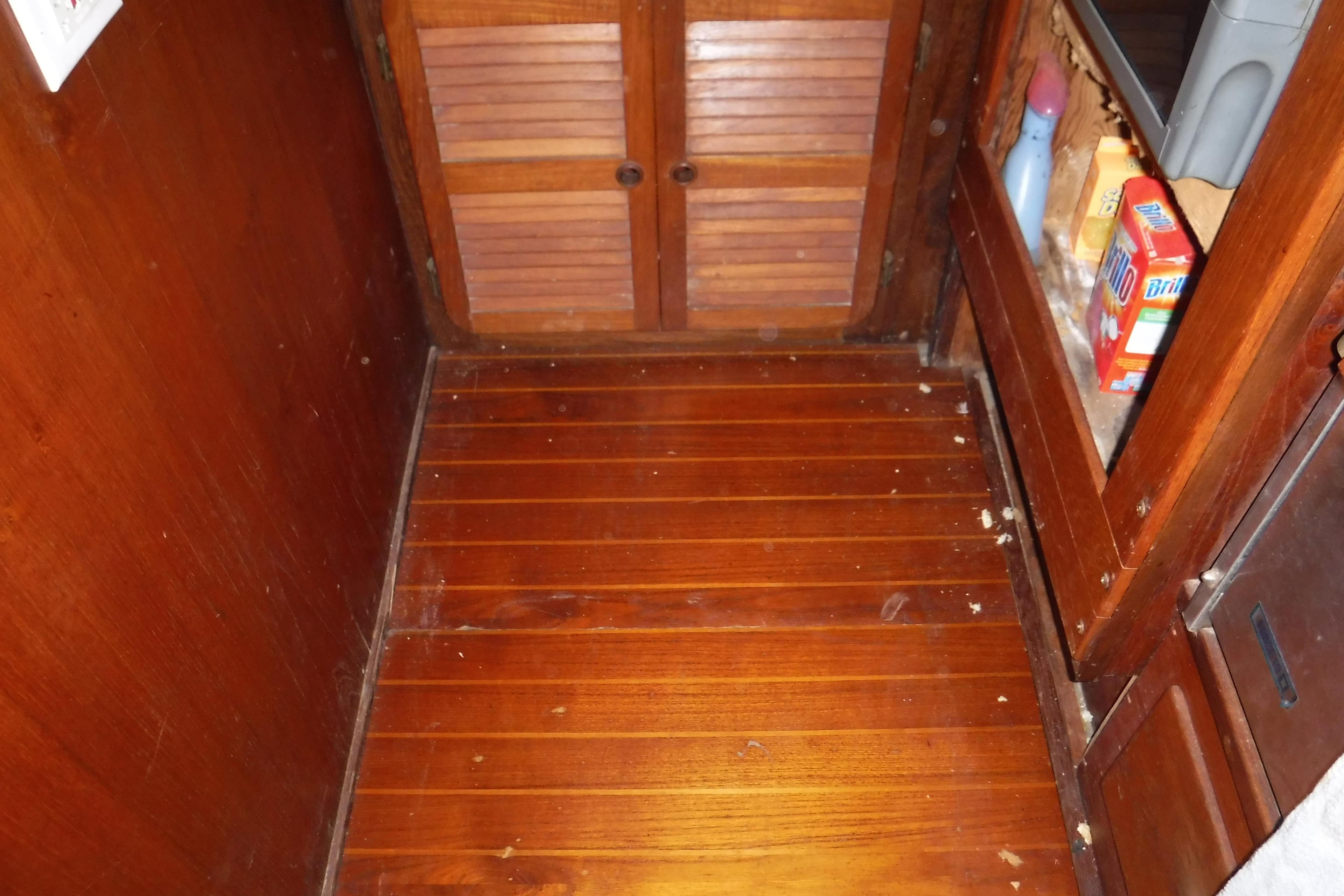 Wooden interior of 1988 Dudley Dix Echo 38 sailboat, featuring storage and cleaning supplies.