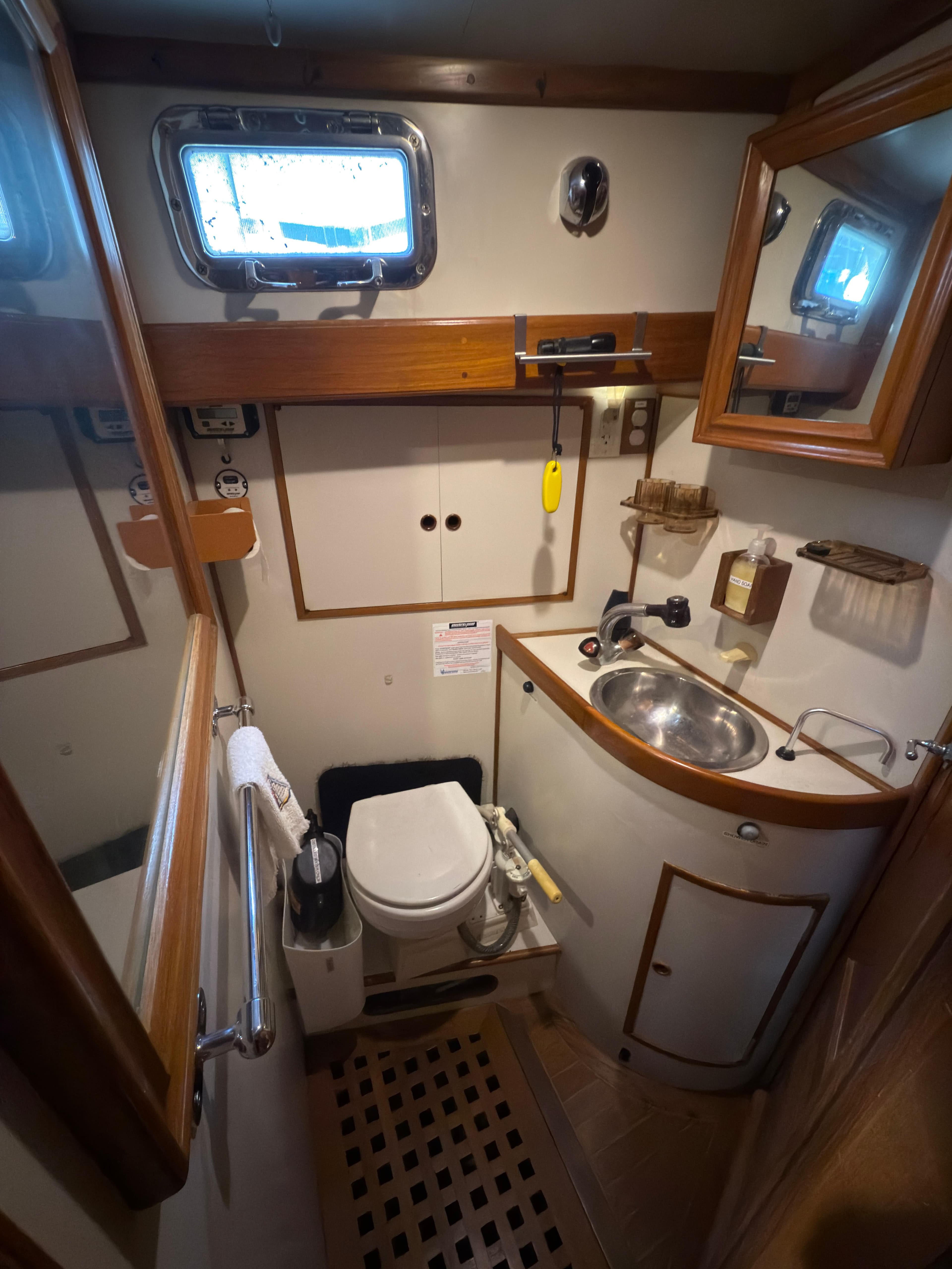 Compact bathroom in 1984 Spindrift Cutter yacht, featuring sink, toilet, and wooden accents.