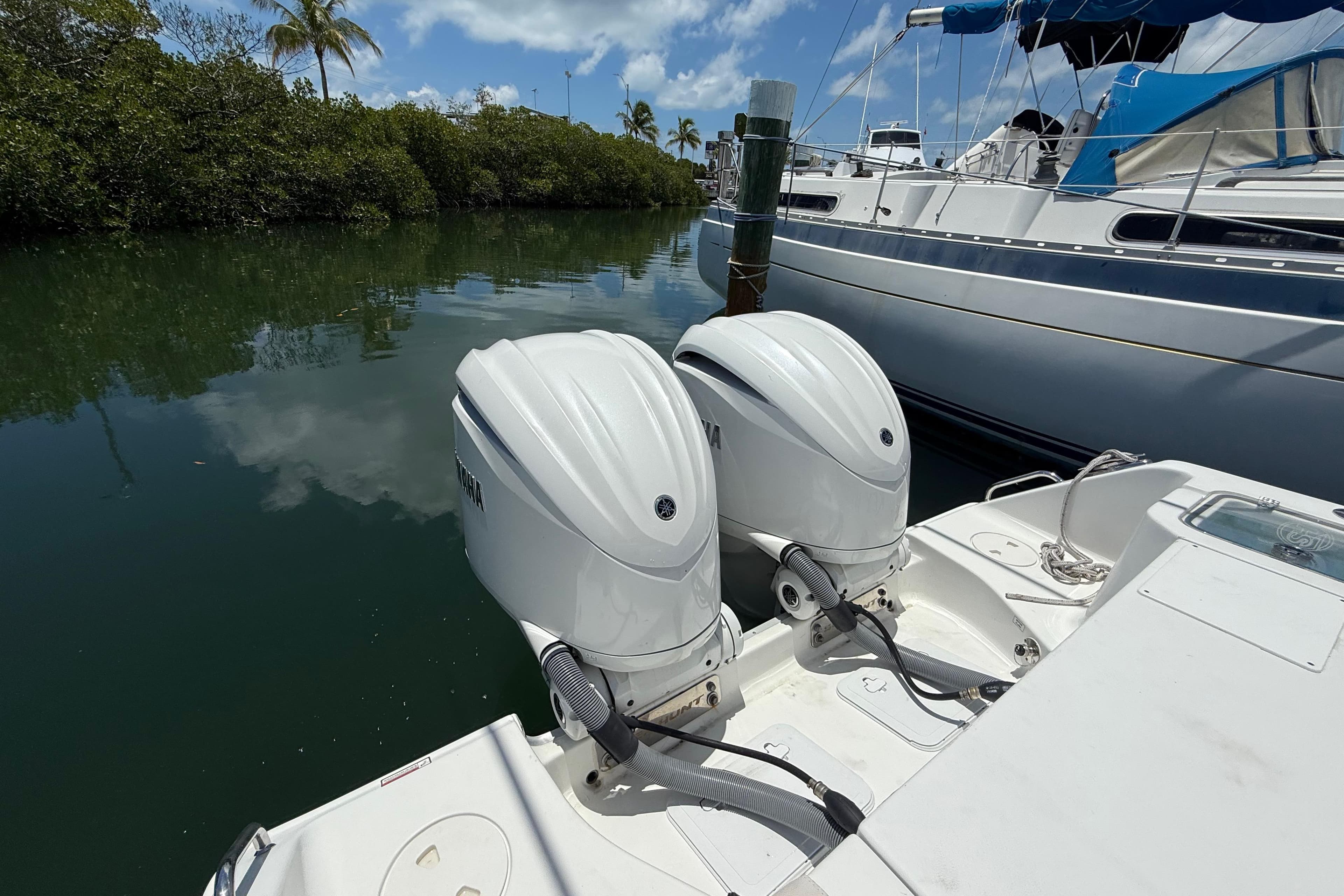 Twin outboard engines on a 2022 Sea Hunt Gamefish 30 Coffin Box boat docked by mangroves.