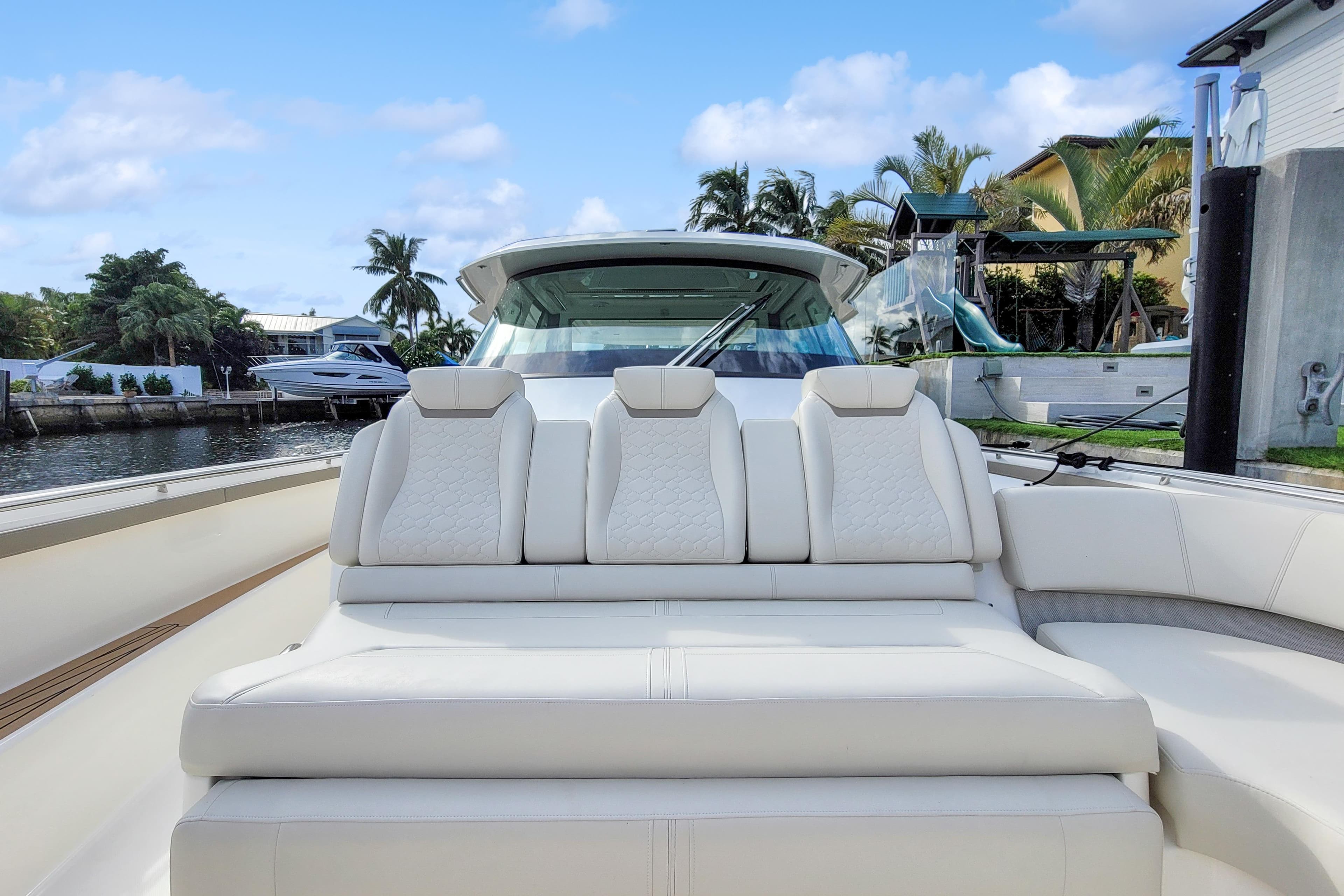 2022 Tiara Yachts 48 LS luxury seating, docked by waterfront homes, under blue skies.