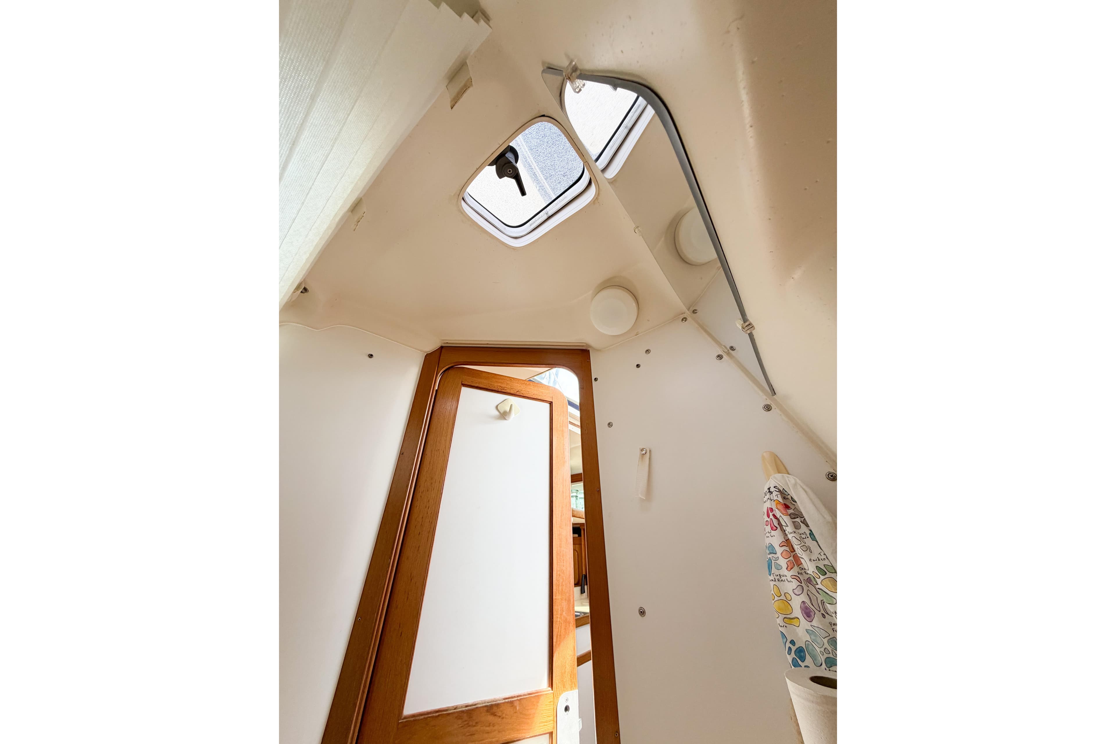 Interior view of a 2003 Catalina 34 MkII sailboat cabin with wooden door and hatch.