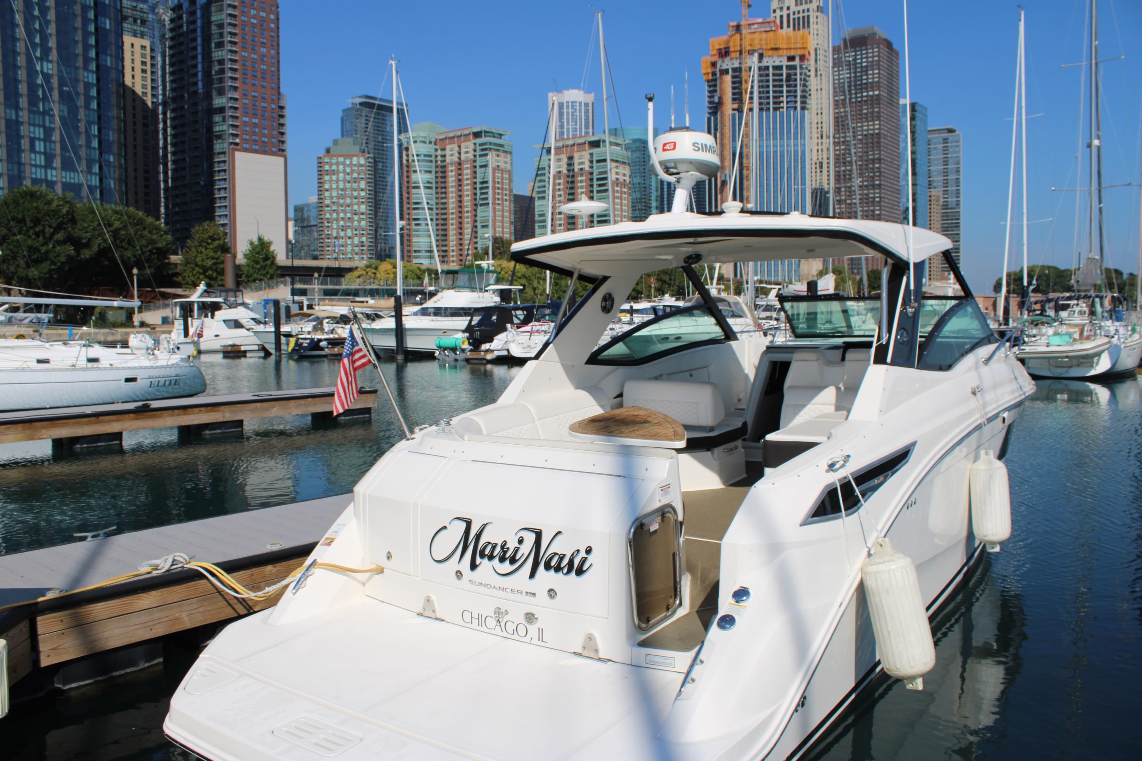 2019 Sea Ray Sundancer 320 docked in a marina with city skyline backdrop.