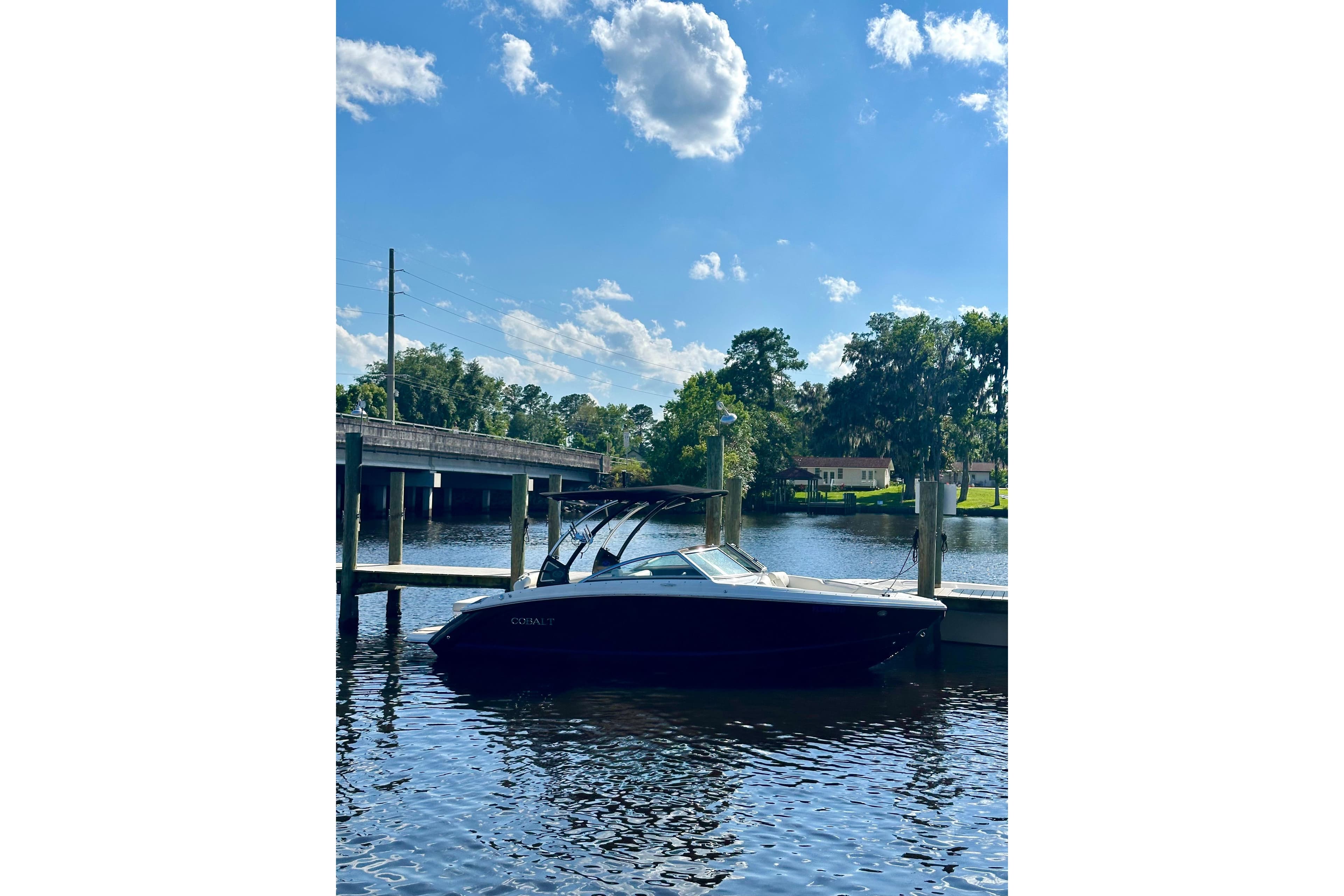 2017 Cobalt R3 boat docked on a sunny river with blue skies.
