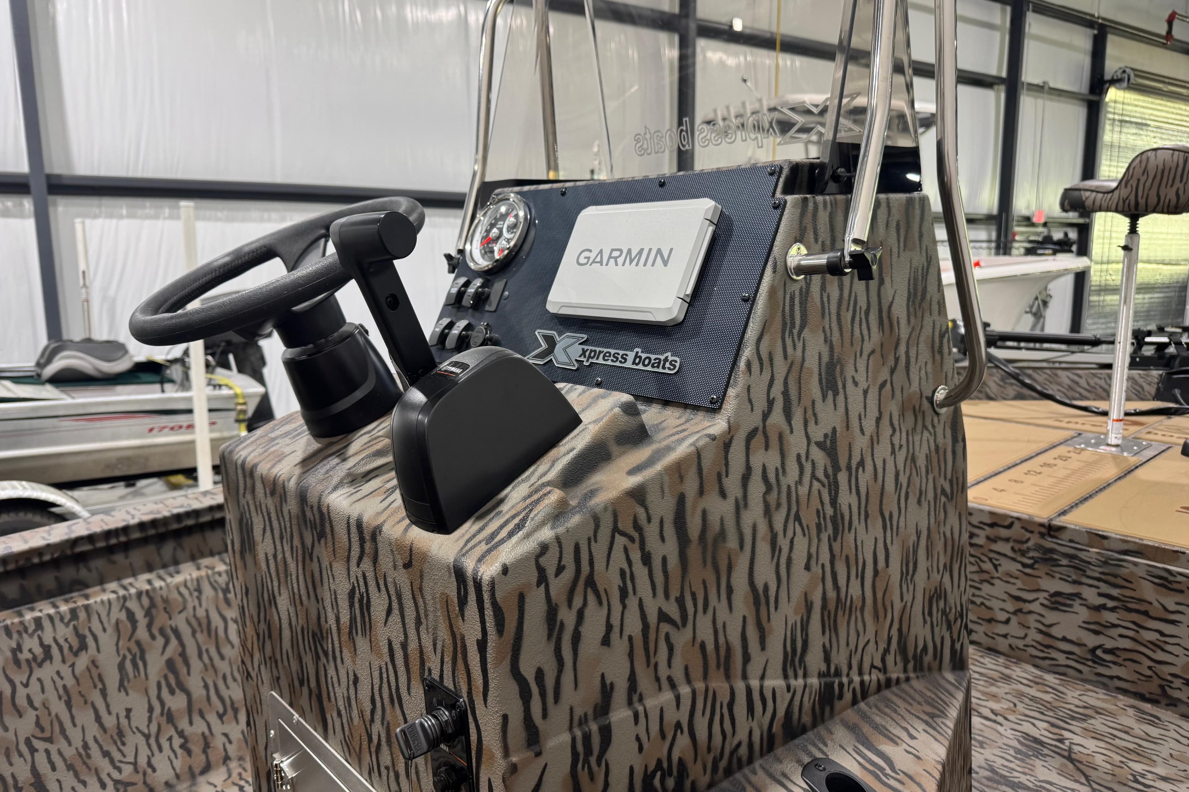 2025 Xpress H190B Bay boat console with Garmin navigation system in a showroom.