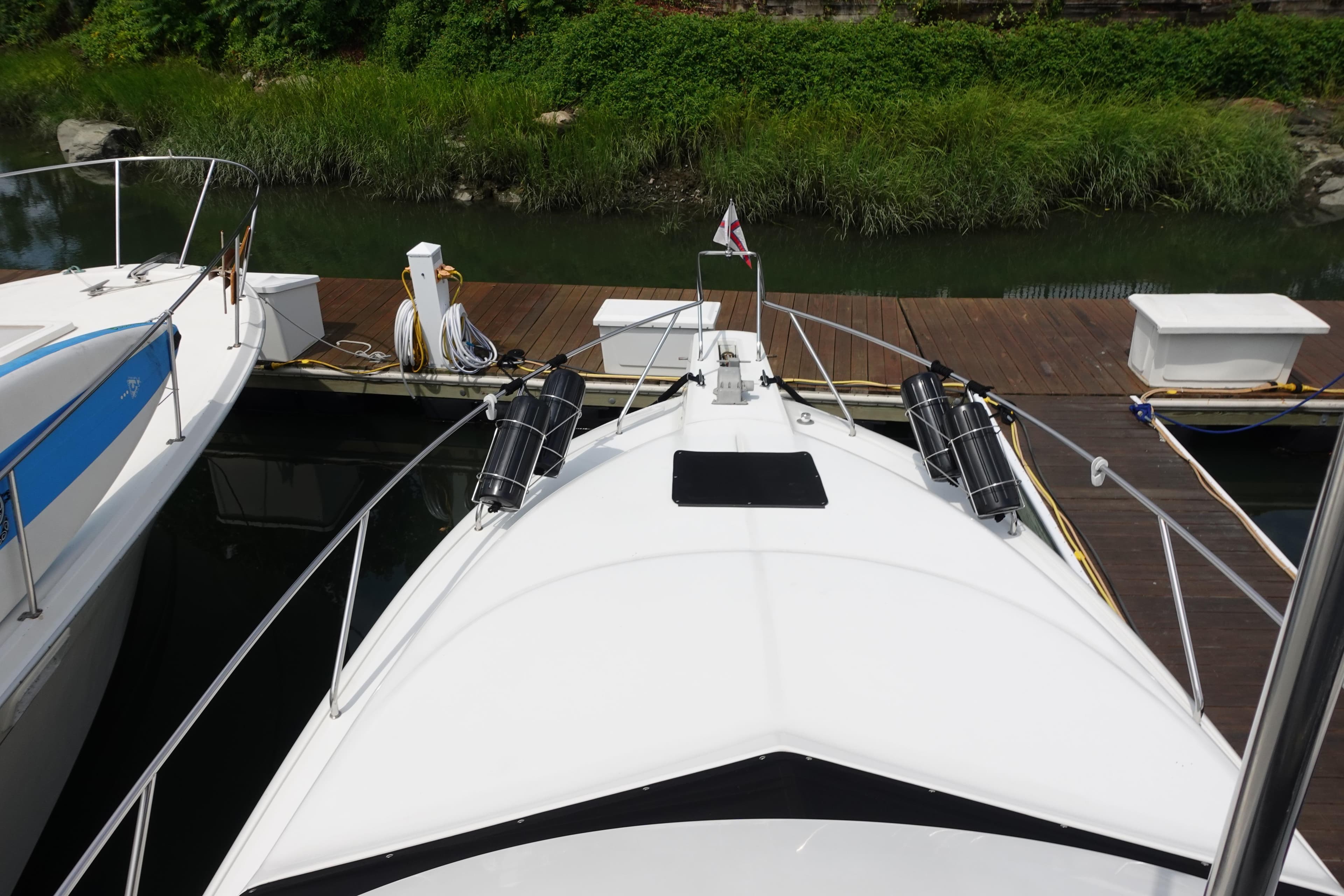 1993 Silverton 31 Convertible docked, view from bow, surrounded by greenery.