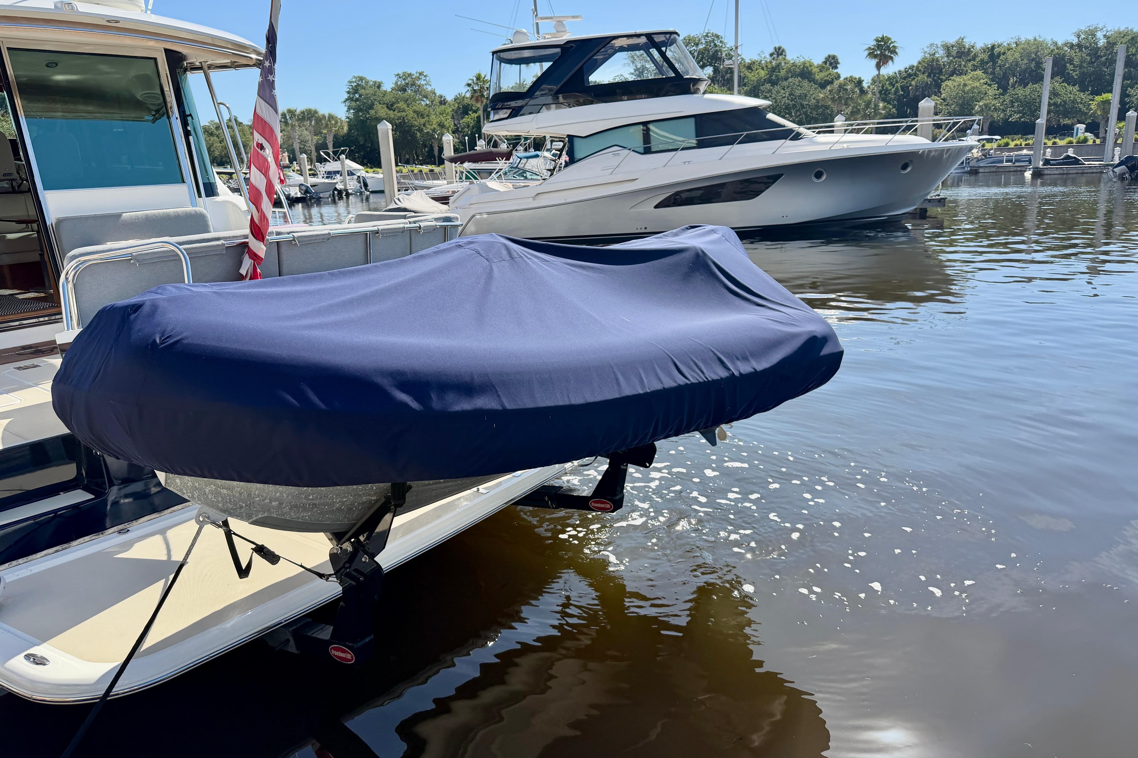 2016 Sabre 48 Salon Express yacht docked with covered dinghy, marina background.