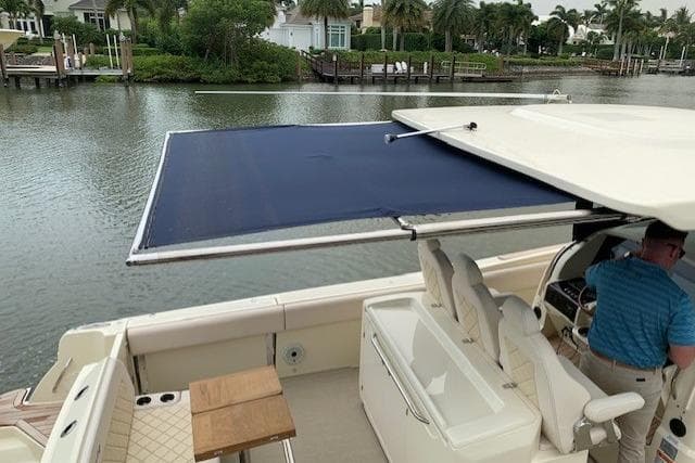 2020 Chris-Craft Catalina 34 boat with extended sunshade, docked by a scenic waterfront.
