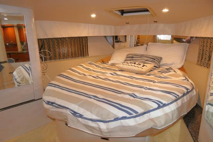 Cozy cabin interior of 2003 Thunderbird Formula 40PC with striped bedding and nautical decor.