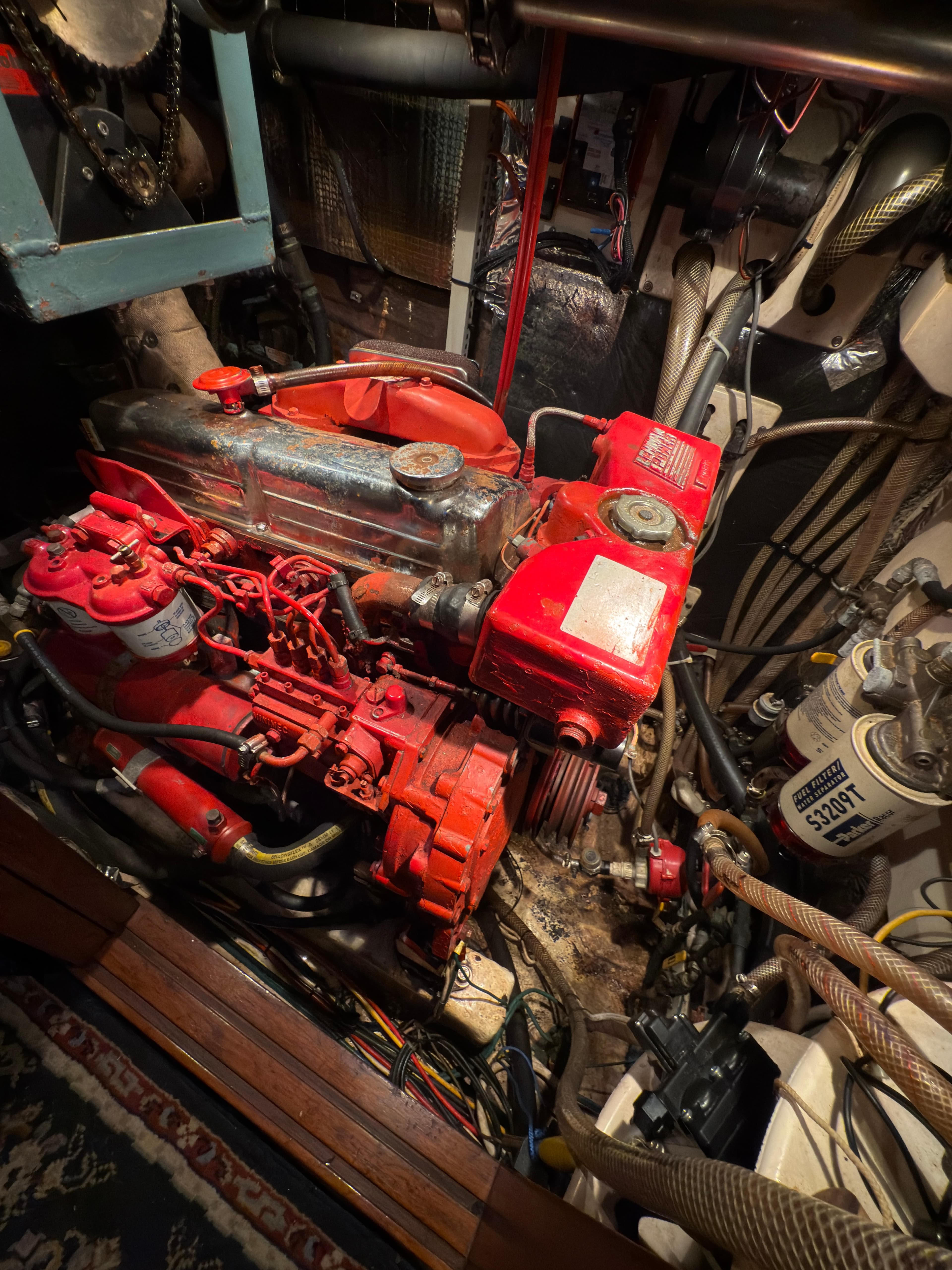 Engine room of a 1984 Spindrift Cutter sailboat, featuring a red marine engine.