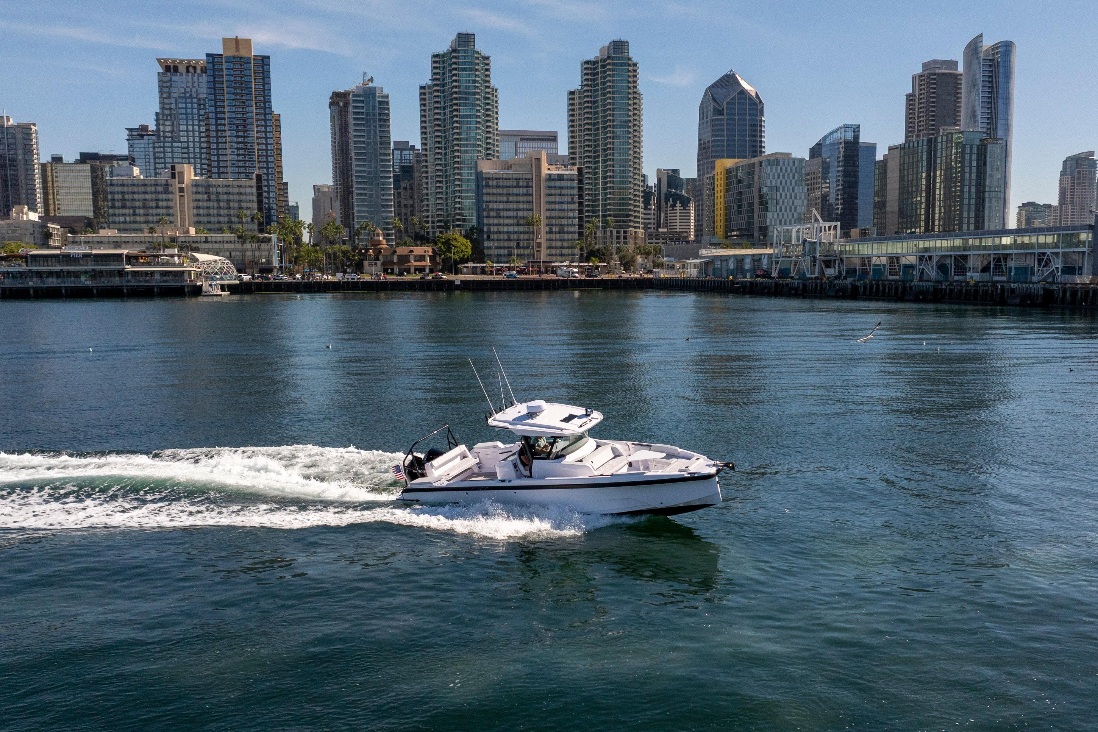 2026 Axopar AX29 CCX cruising near city skyline on a sunny day.