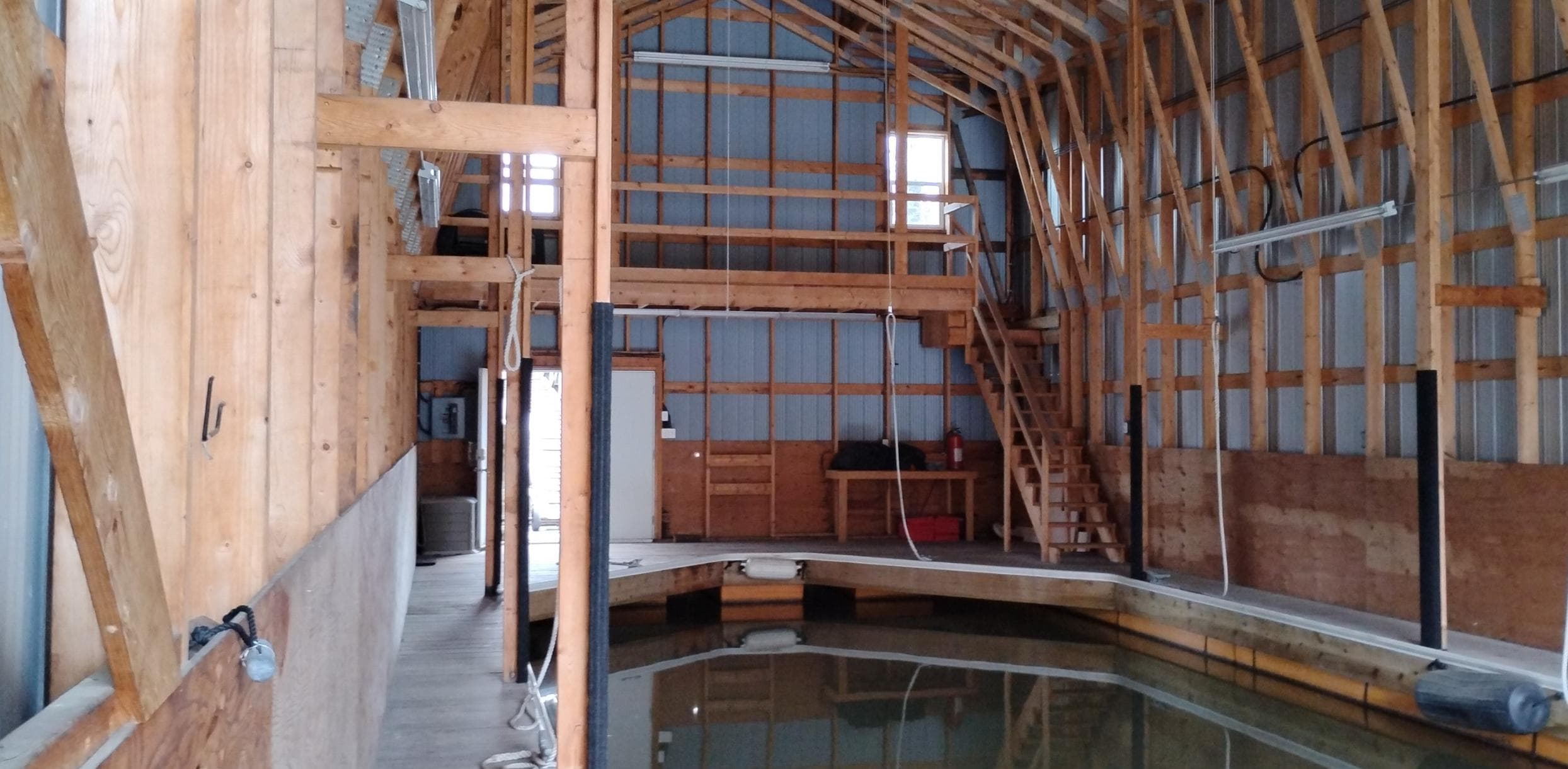 Interior of a custom 2012 boathouse with wooden beams and indoor water dock.