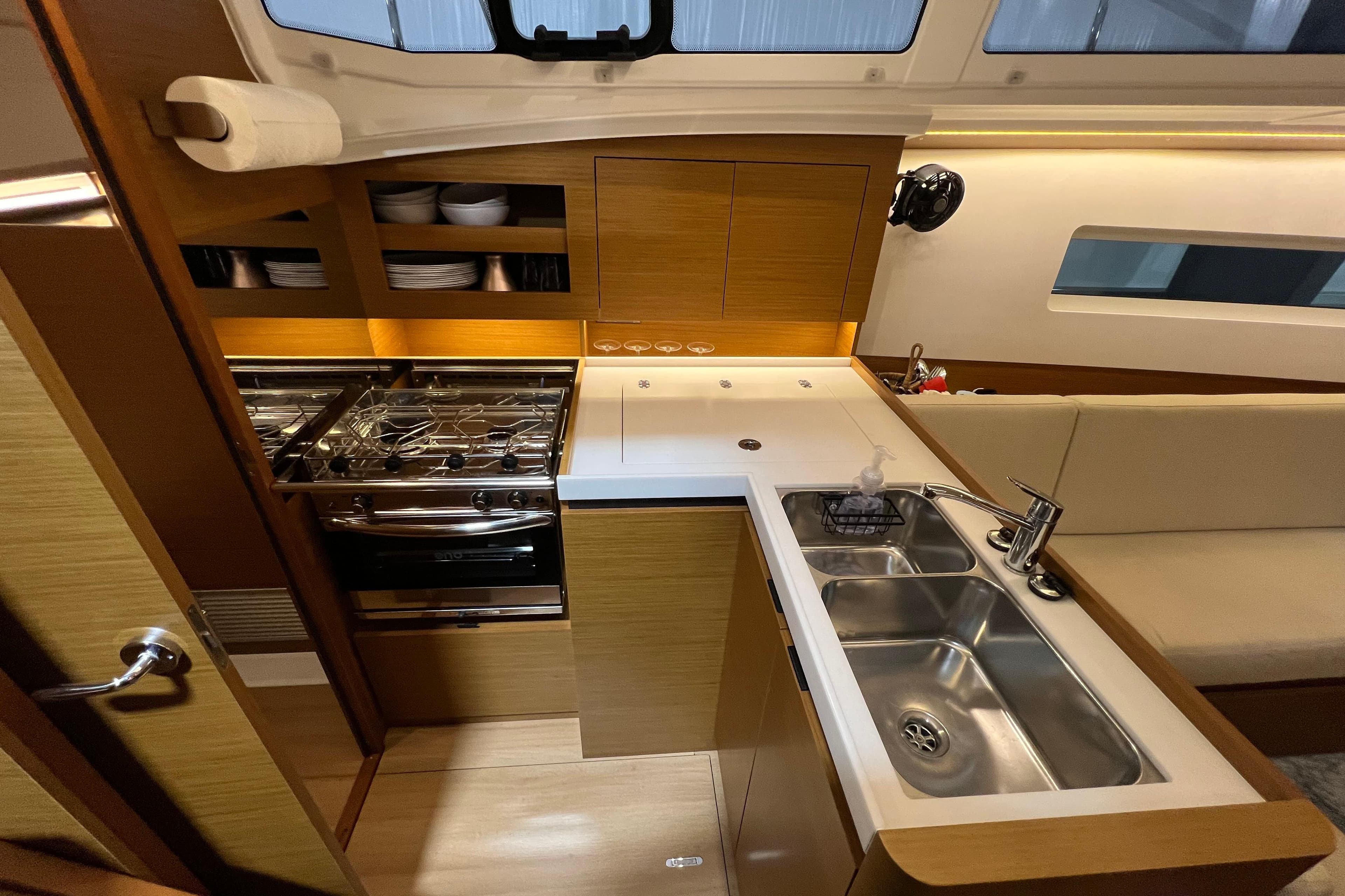 Modern kitchen interior of 2023 Jeanneau Sun Odyssey 380 yacht, featuring sleek design and amenities.