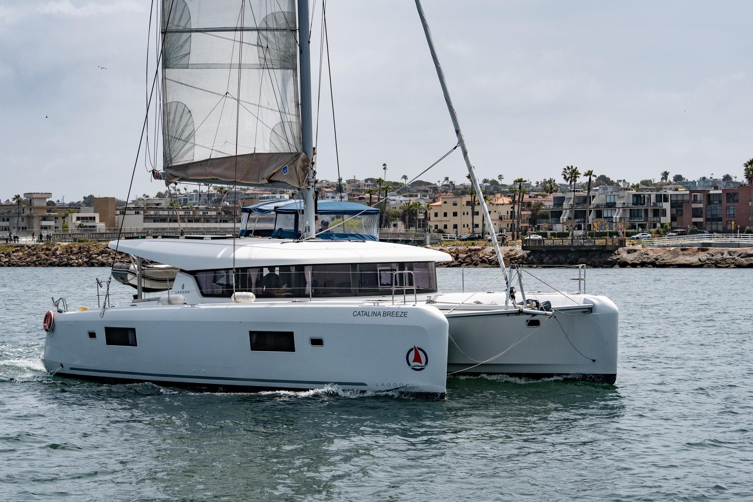 2022 Lagoon 42 catamaran sailing near coastal buildings.