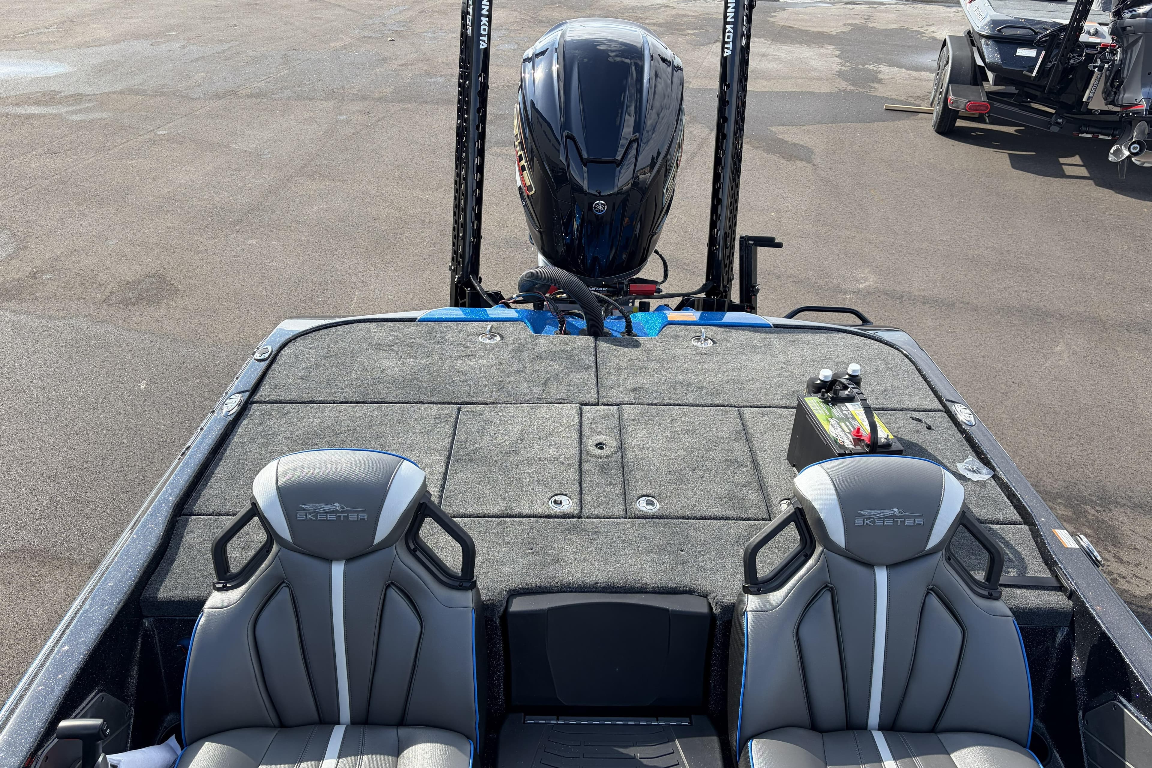 2026 Skeeter ZXE21 boat interior with dual seats and motor, parked on asphalt.