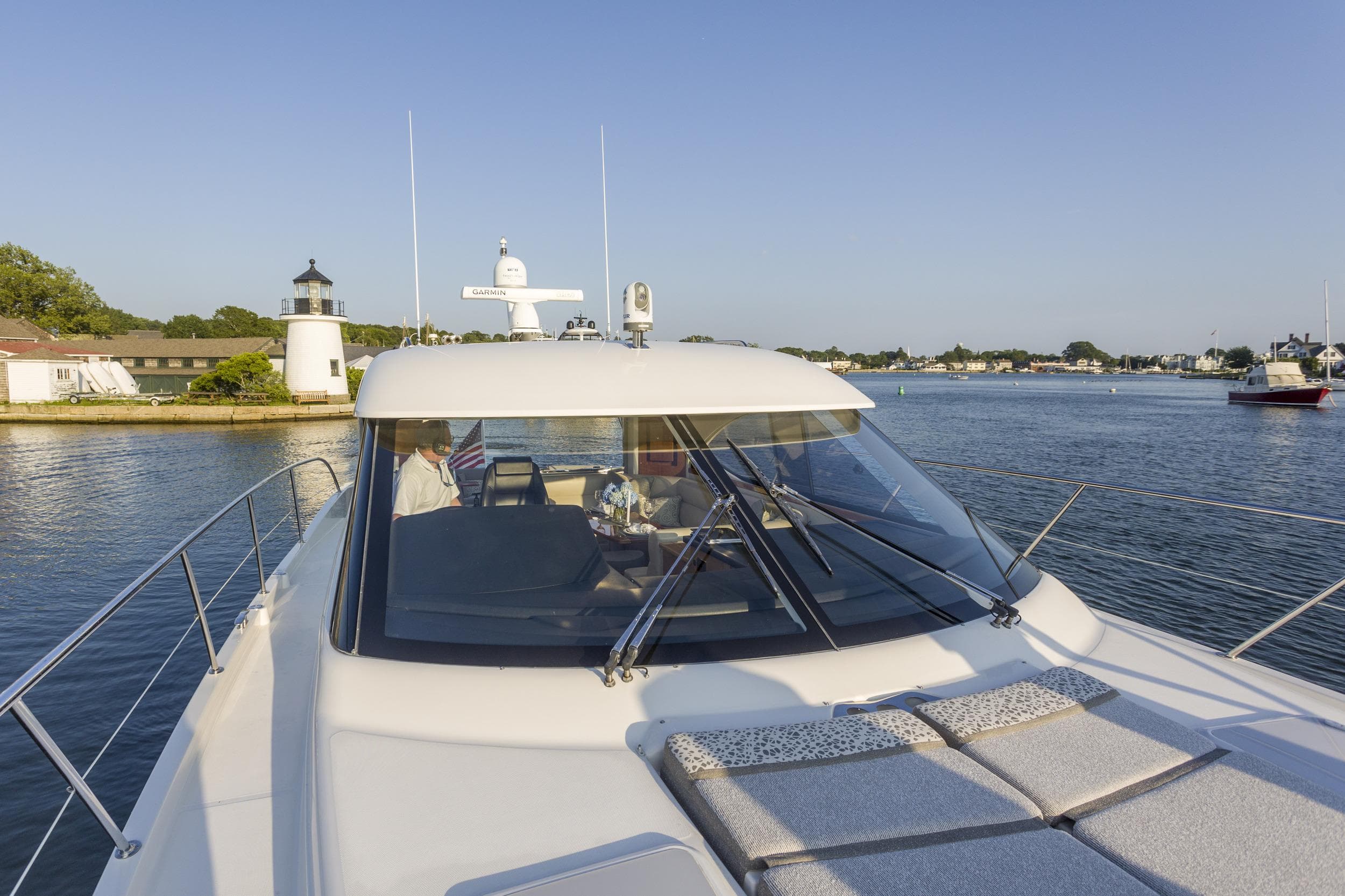 2016 Riviera 5000 Sport Yacht cruising near a lighthouse on a sunny day.