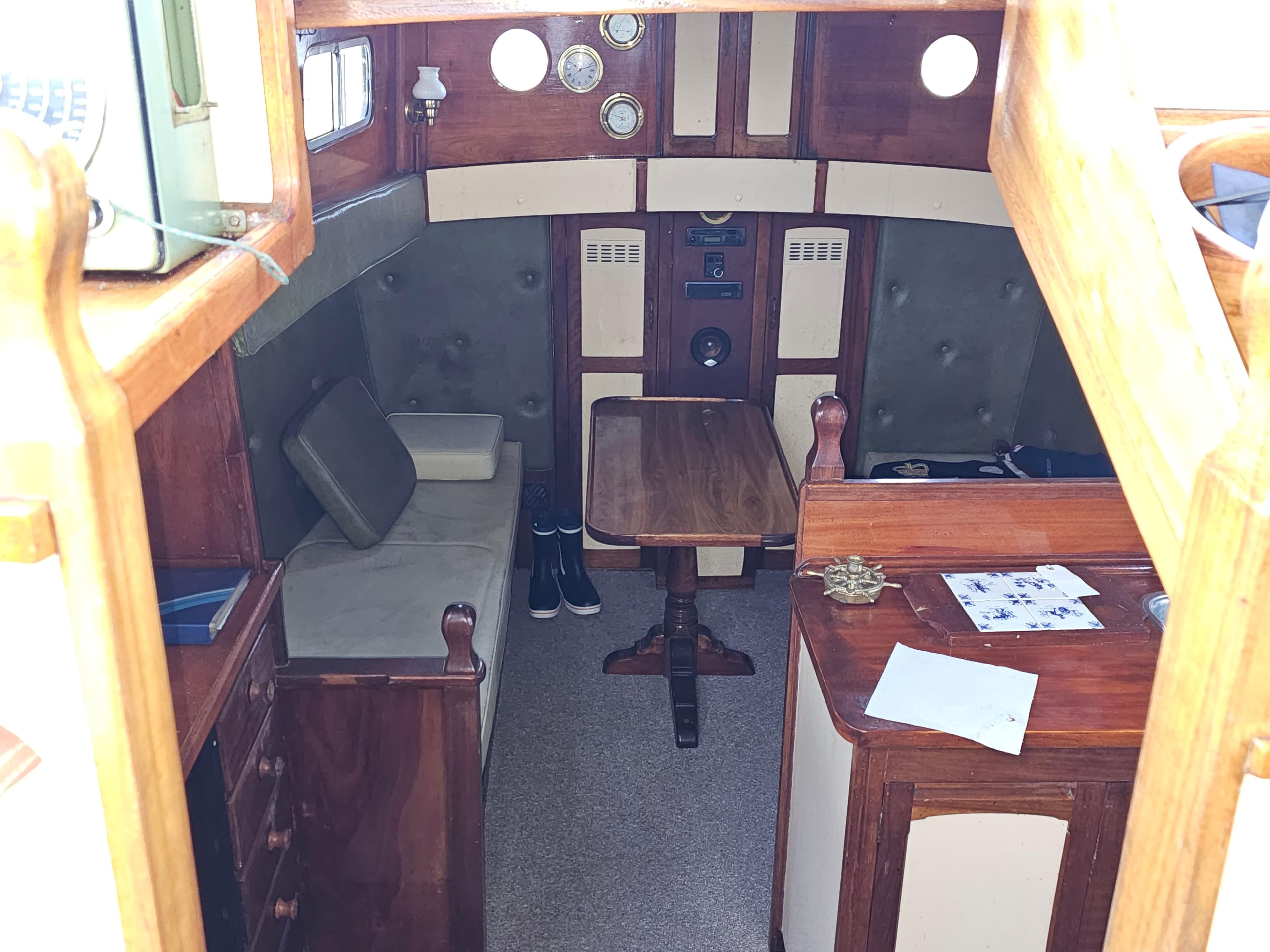 Interior of 1978 Custom John Bain TSMY boat with wooden furnishings and cozy seating area.