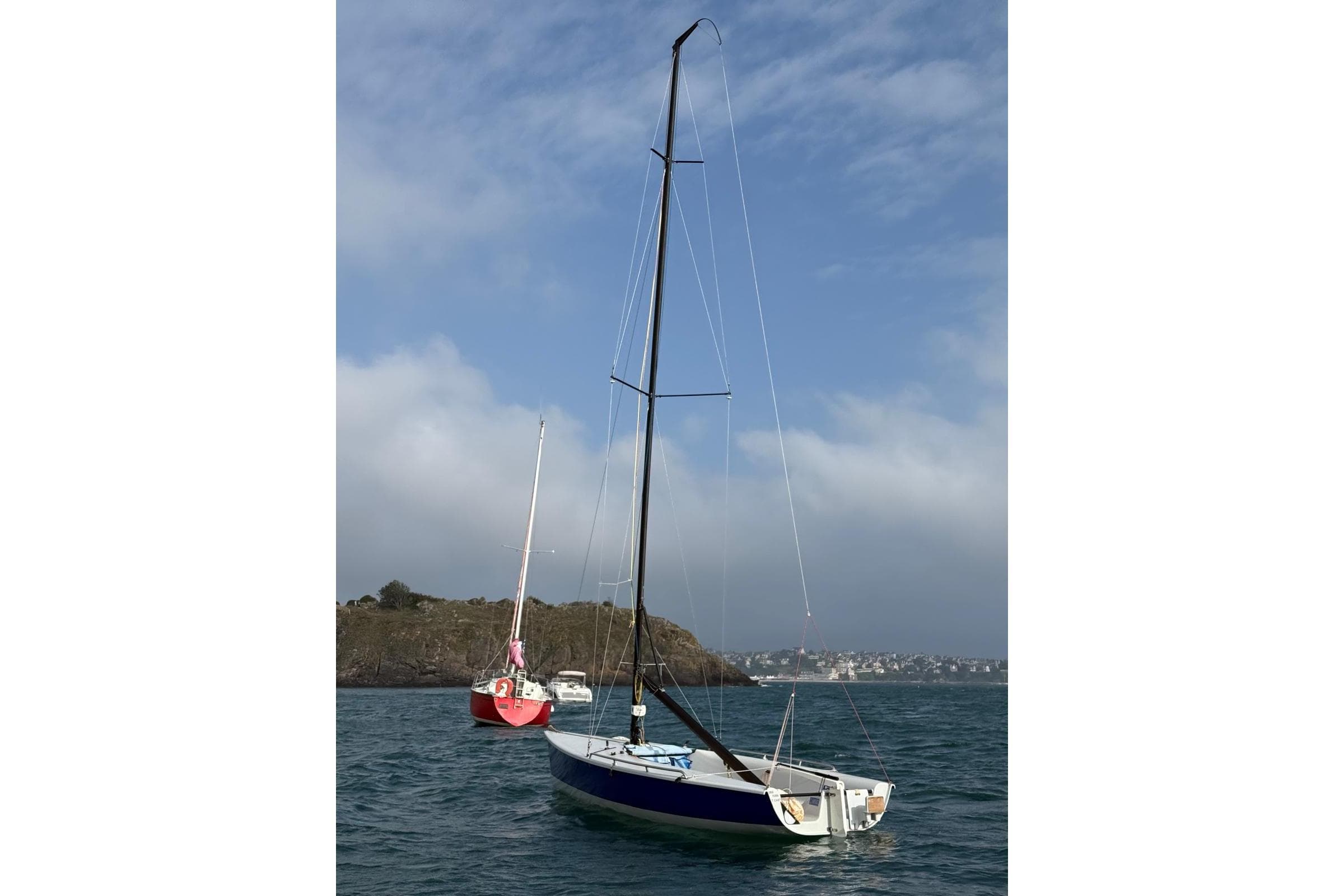 Sailboats anchored in a scenic bay, featuring a 2003 Laser SB3 model.