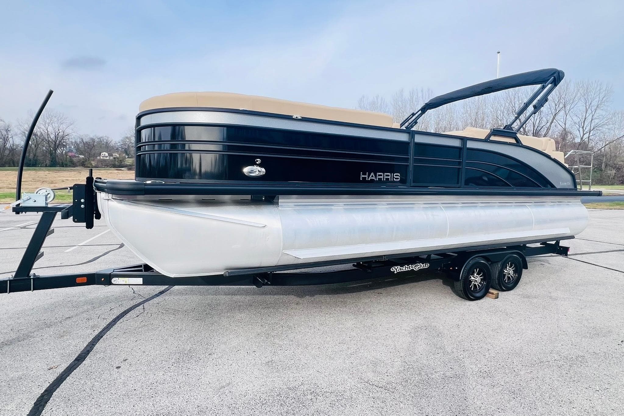 2024 Harris Sunliner 250 pontoon boat on trailer in parking lot.