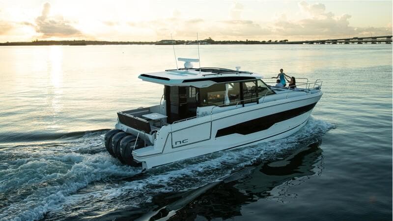2025 Jeanneau NC 1295 Coupe cruising on calm waters at sunset.