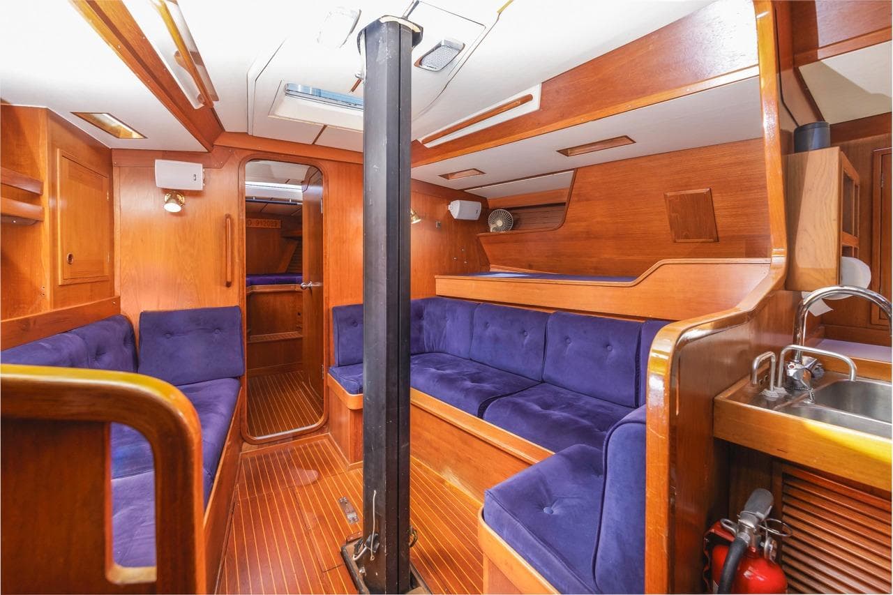 Interior of 1983 Baltic 42 DP yacht with wooden finish and blue seating.