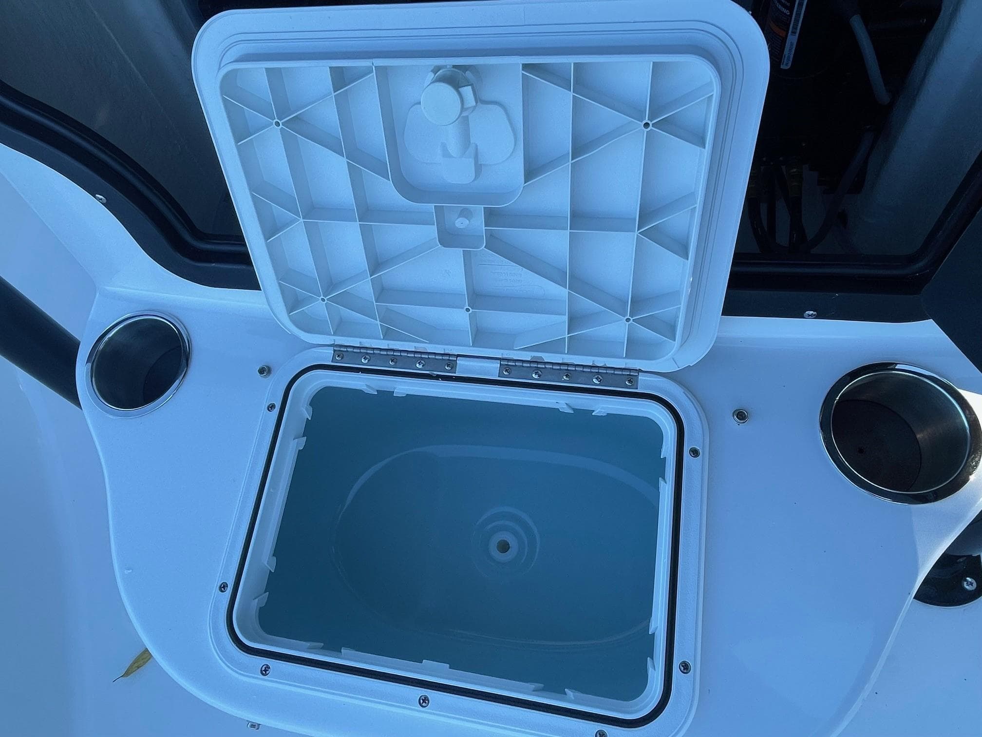 Open storage compartment on 2025 Sea Pro 210 DLX boat with cup holders.