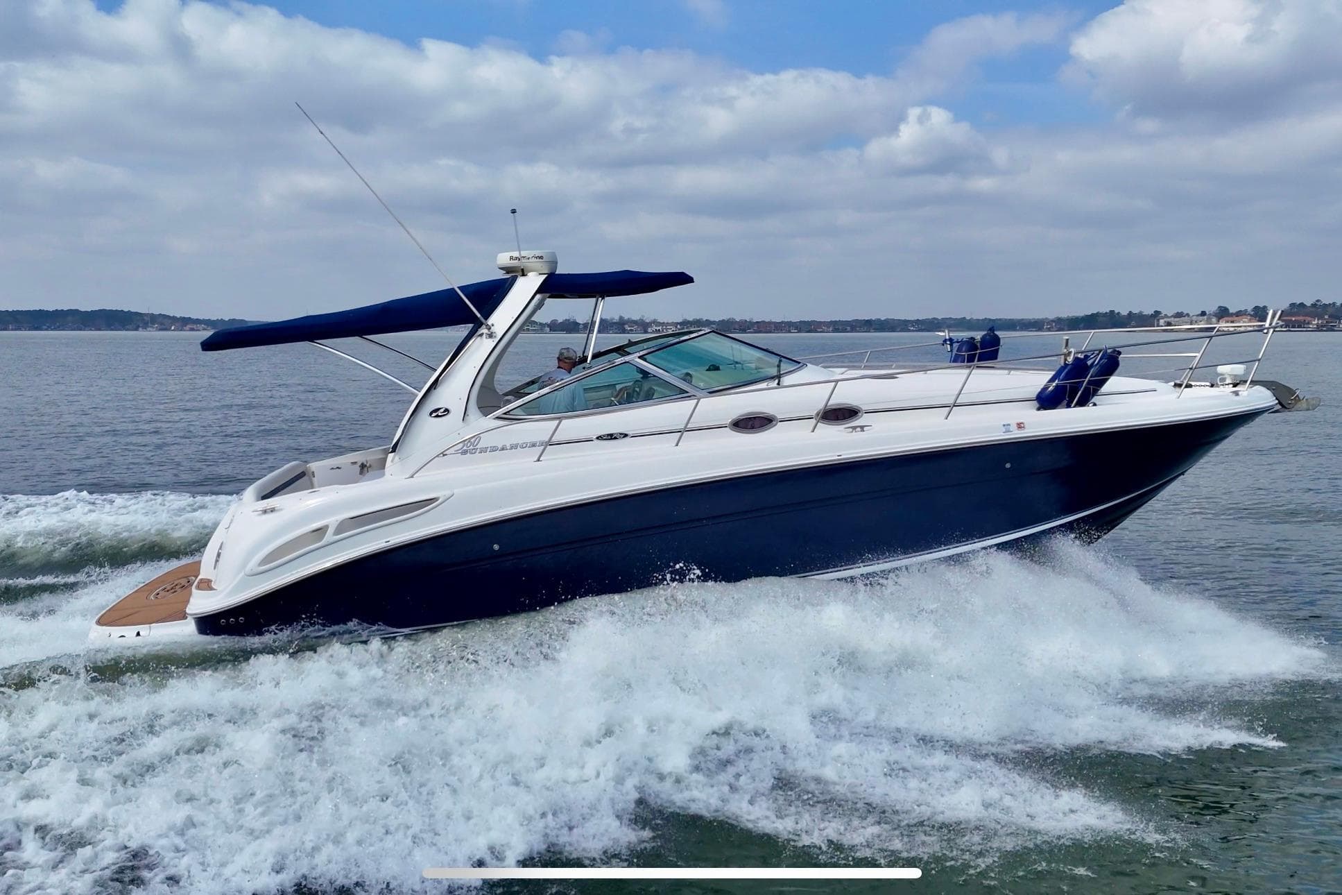 2005 Sea Ray 360 Sundancer cruising on open water under a cloudy sky.