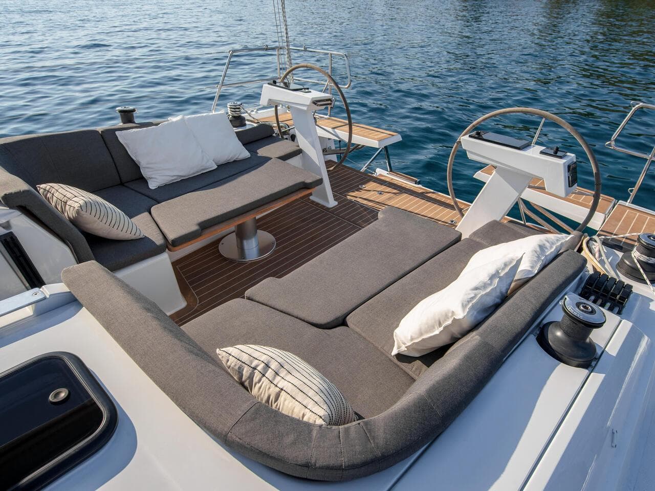Luxurious seating area on 2025 Hanse 410 yacht with cushions and steering wheels.