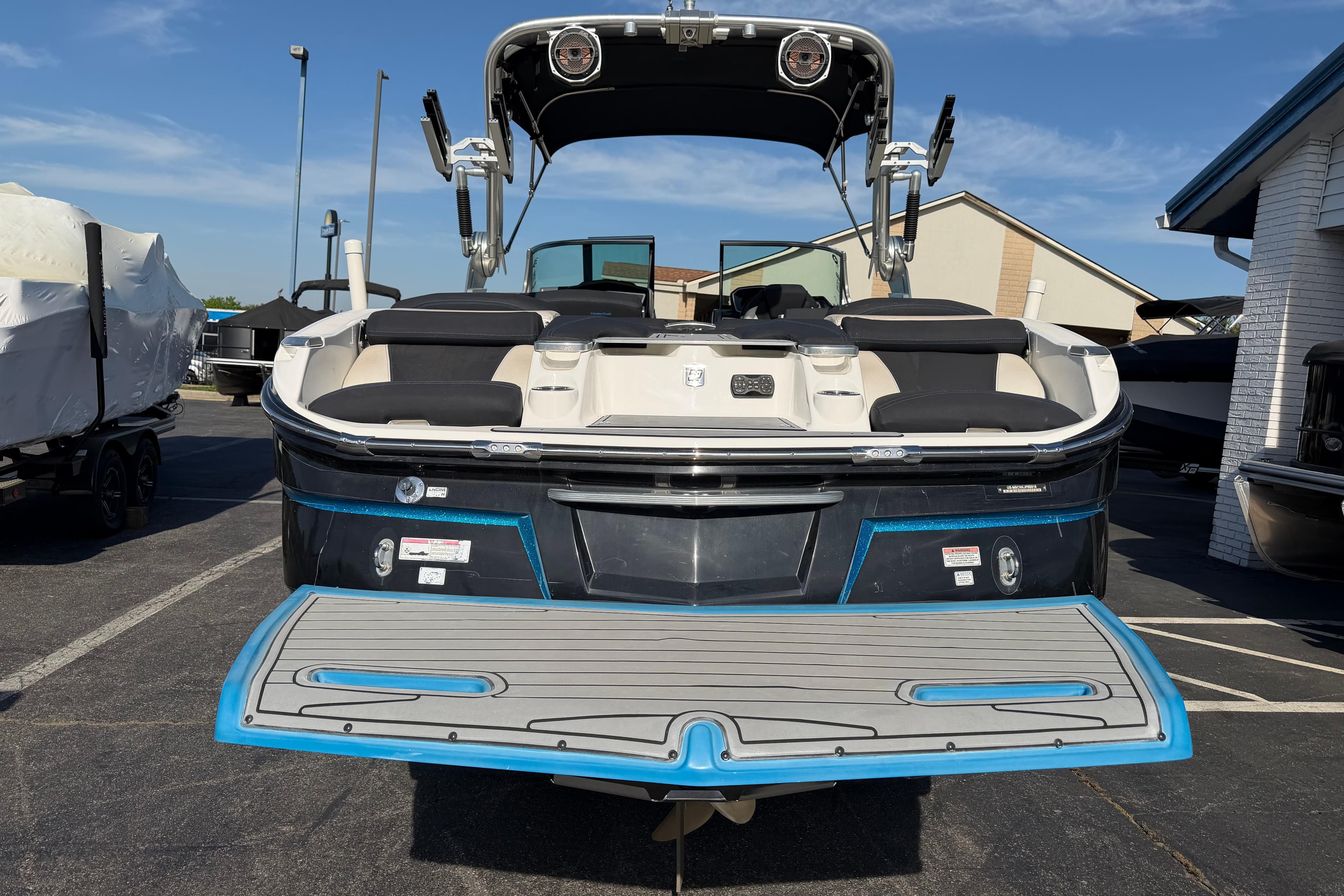 2018 MasterCraft X26 boat with swim platform, parked outdoors under clear sky.