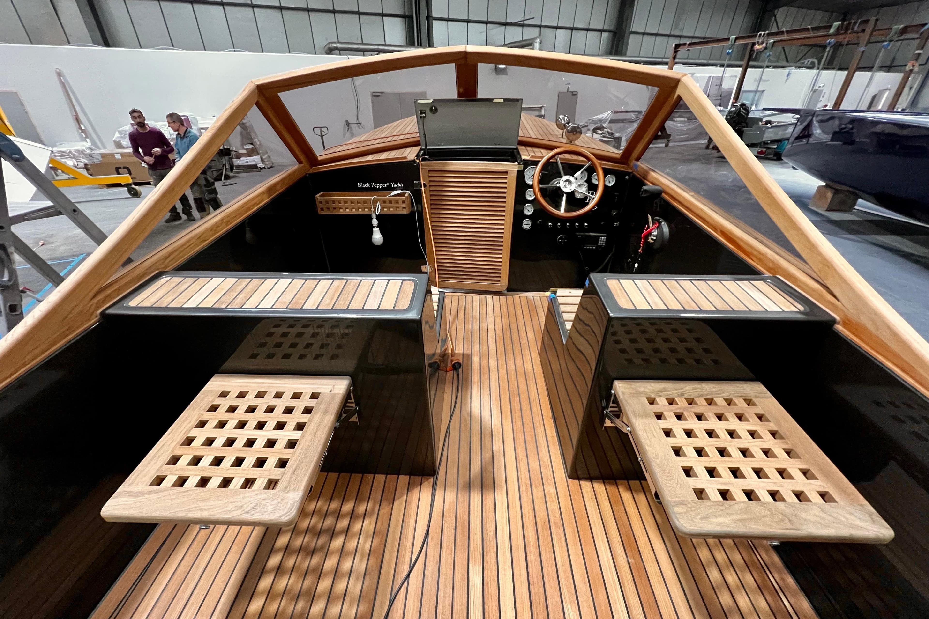 Interior of Black Pepper Tender 24 boat, showcasing wooden deck and steering wheel, 2026 model.