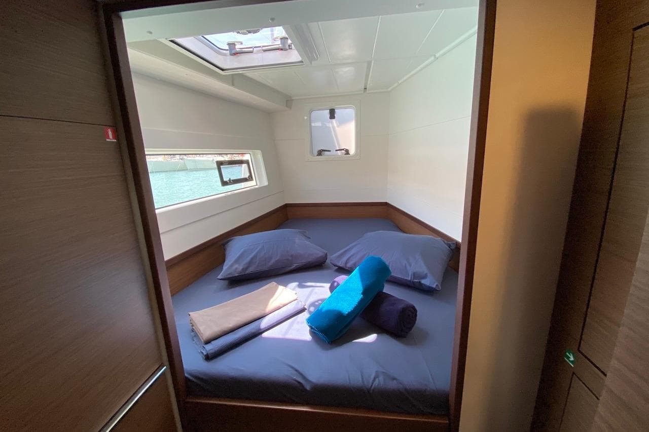 Cozy cabin interior of 2020 Lagoon 40 catamaran with bed and porthole view.