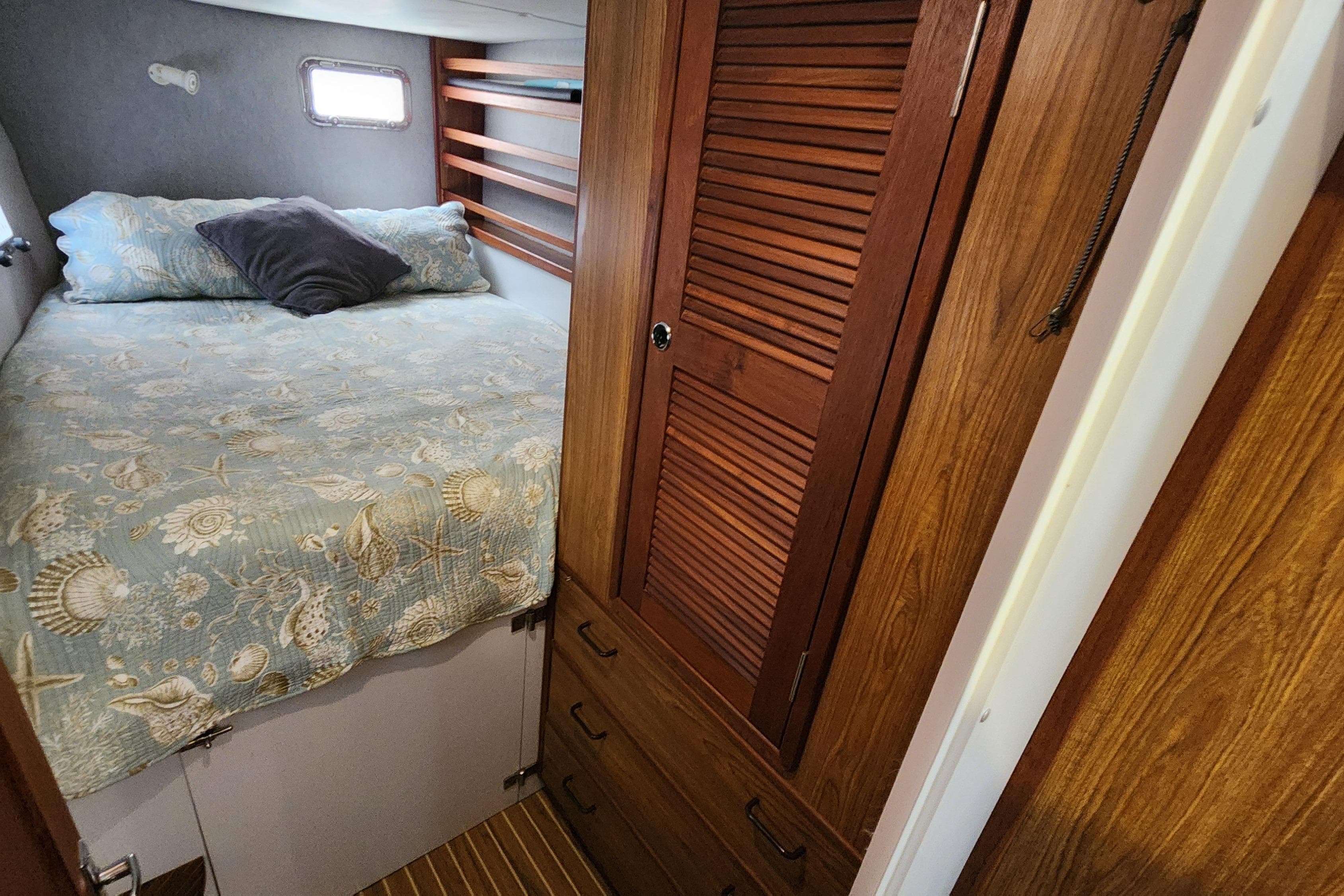 Cozy cabin interior of 2003 Endeavour 44 TrawlerCat with bed and wooden storage.