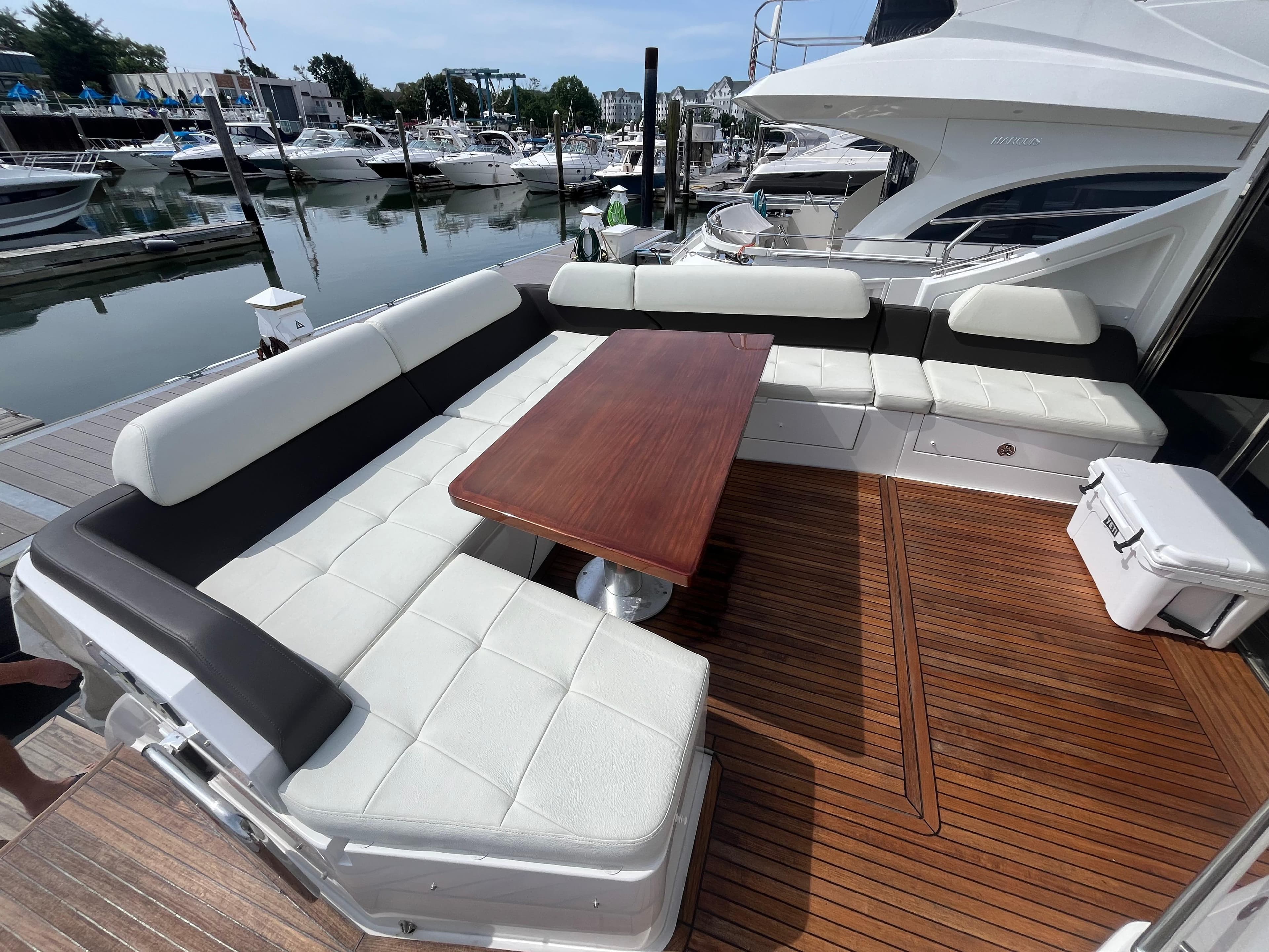 Luxury seating area on 2014 Azimut 55S yacht, featuring elegant wood table and marina view.