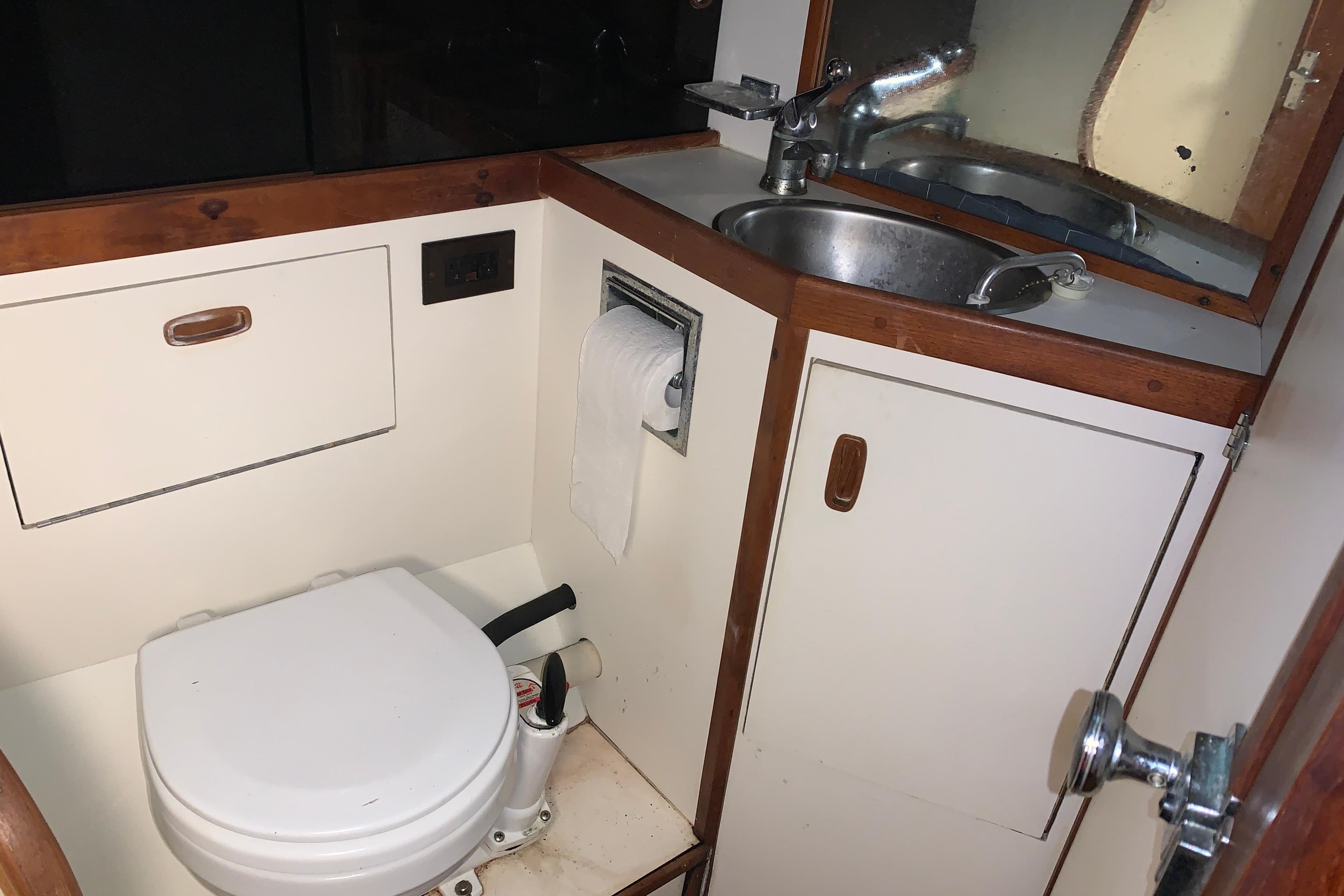 Compact bathroom in a 1984 Sabre 38 sailboat with toilet and sink.