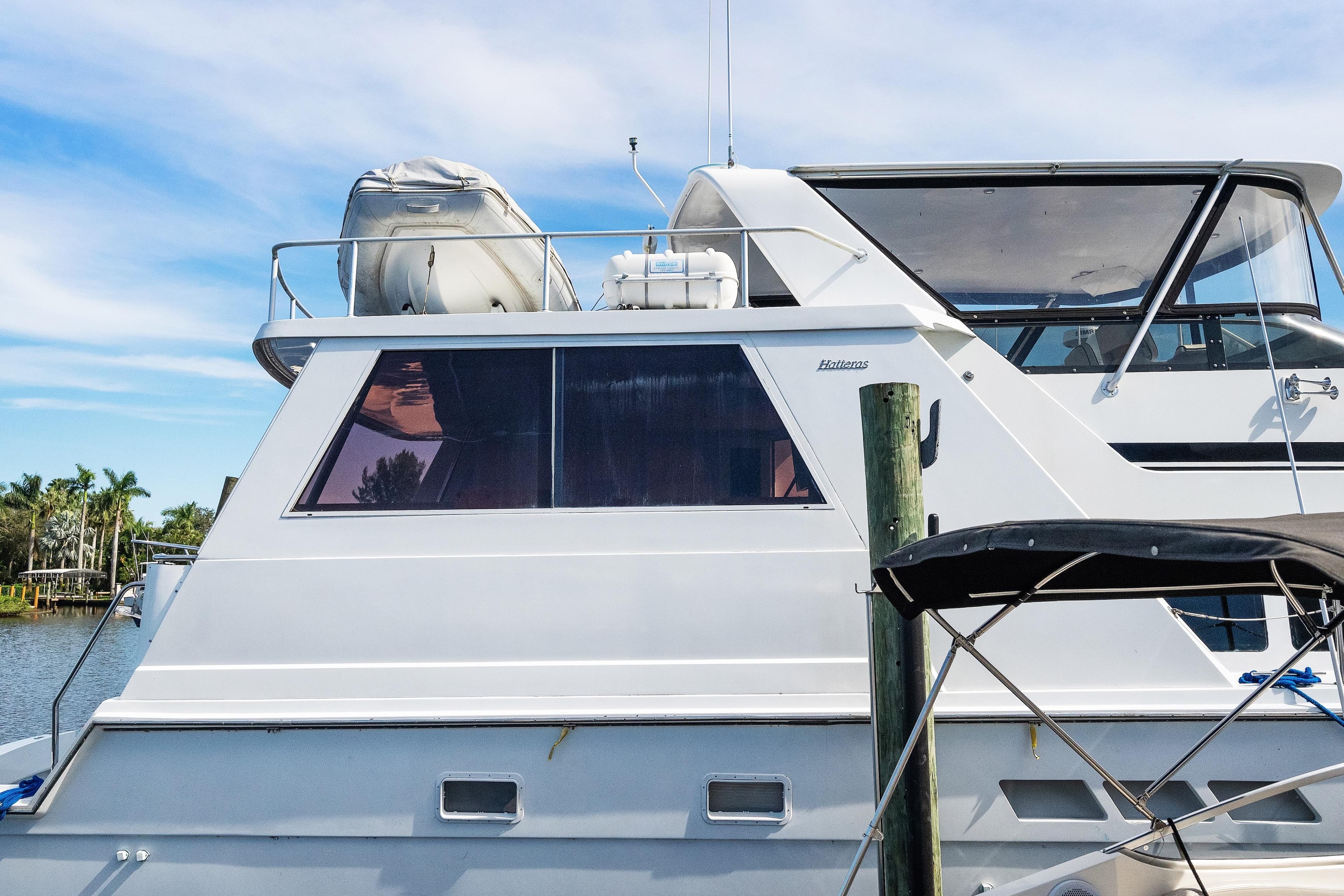 1999 Hatteras 52 Cockpit Motor Yacht docked, featuring sleek design and spacious upper deck.