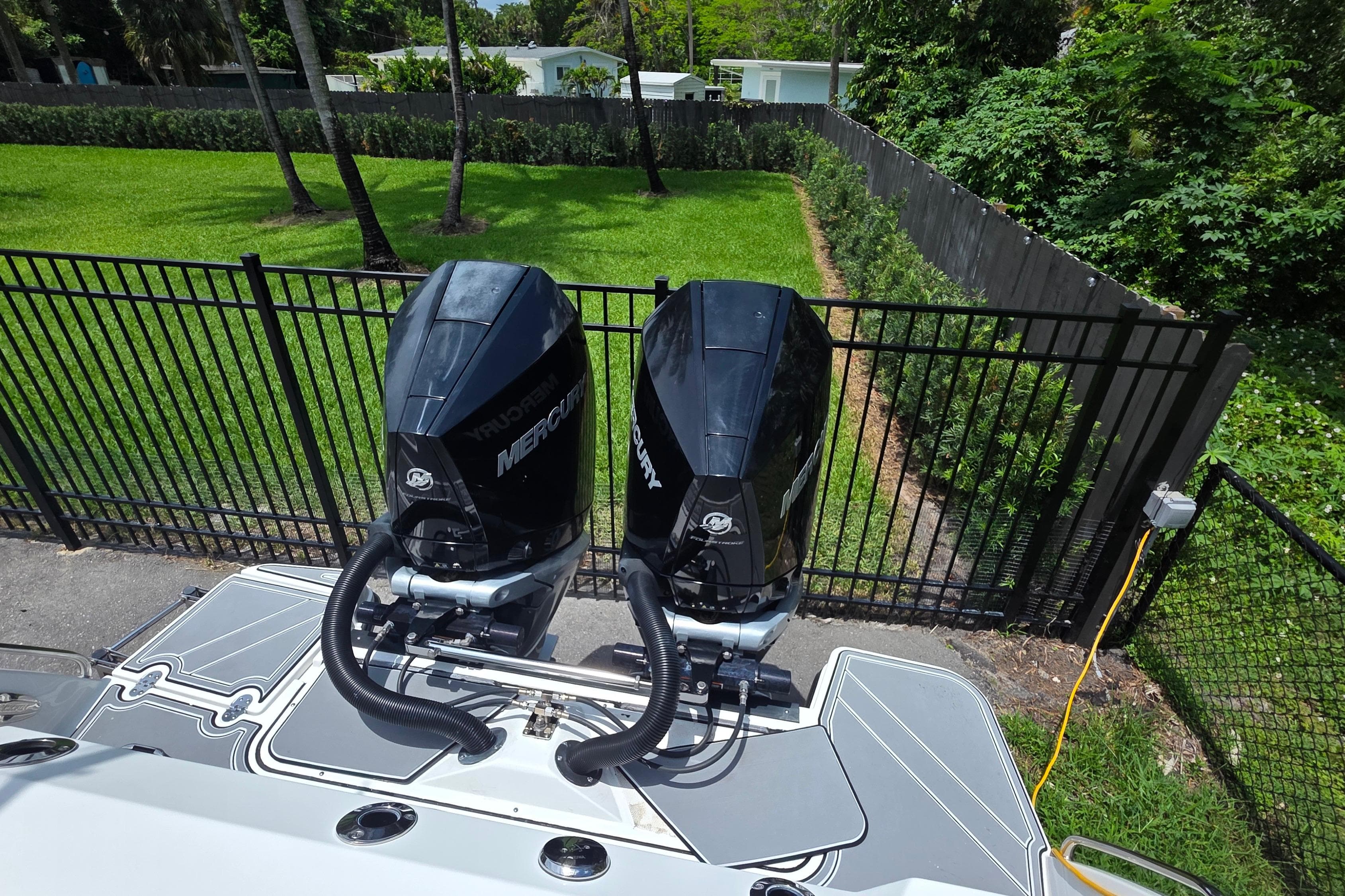 2021 Blackfin 272 CC boat with twin Mercury outboard engines, parked near a fenced yard.